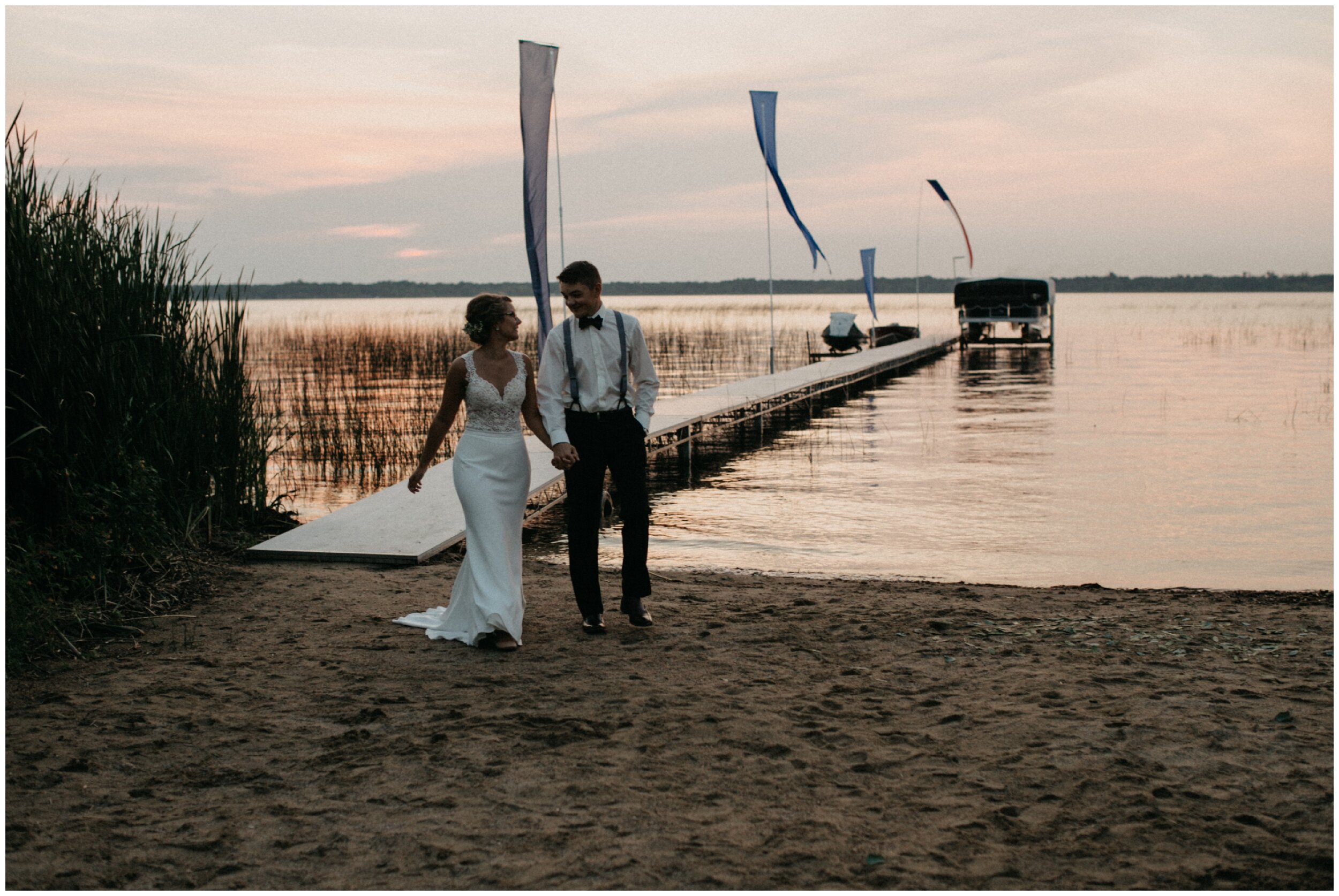 Bride and groom walking on beach during sunset after Brainerd, Minnesota intimate cabin wedding
