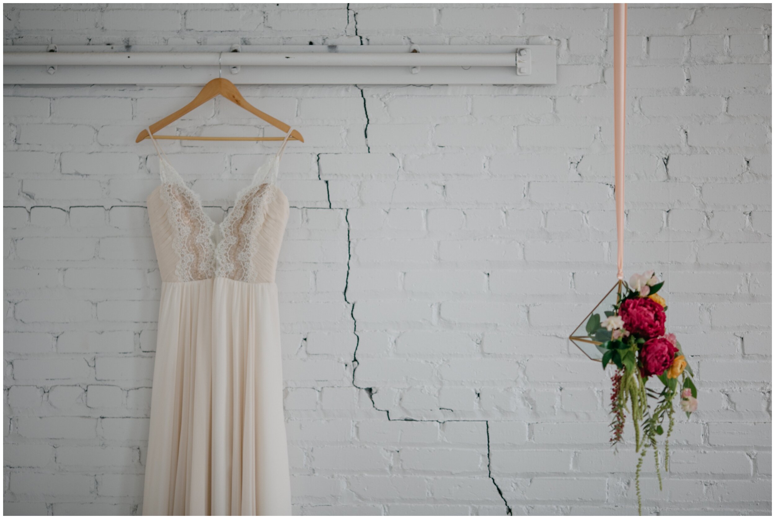 Bride's wedding dress hanging in white, brick,  industrial wedding venue at the Northern Pacific Center in Brainerd, Minnesota