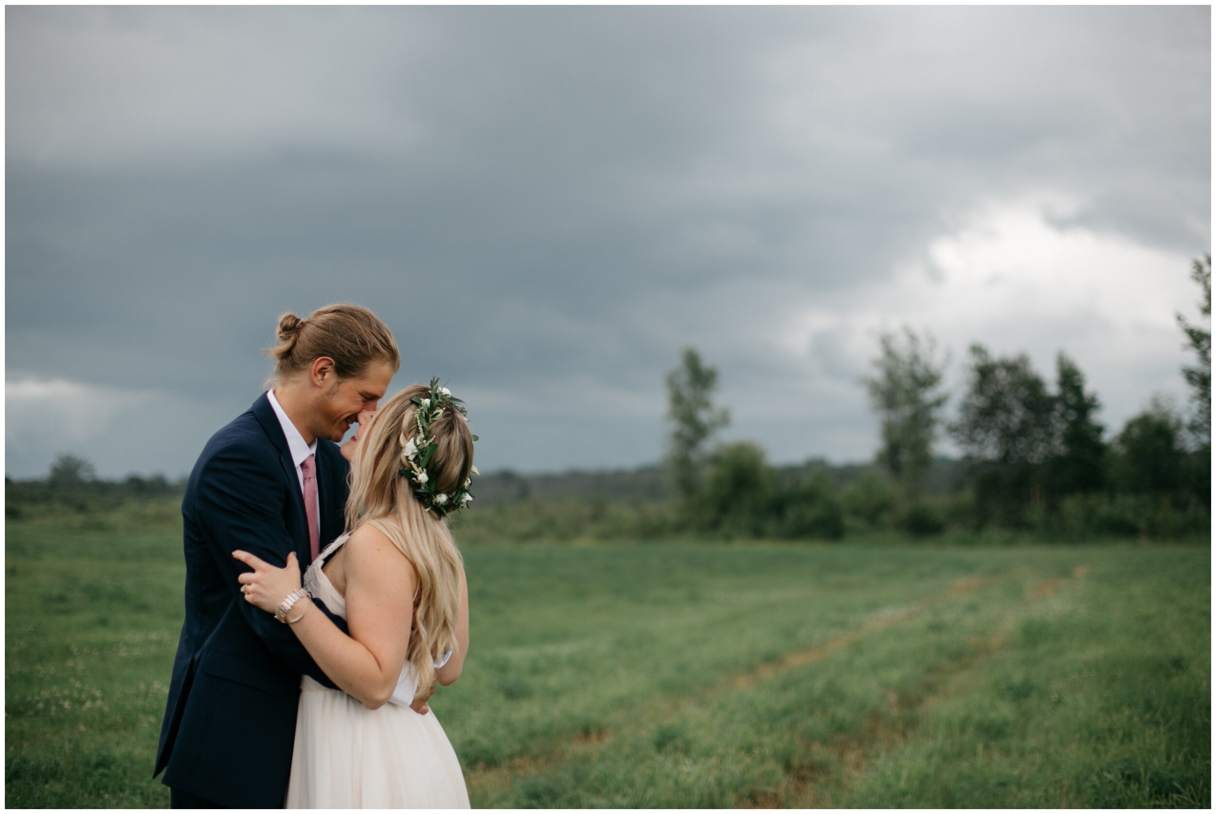 Bride and groom standing in field with stormy sky background at the Northern Pacific Center in Brainerd, Minnesota