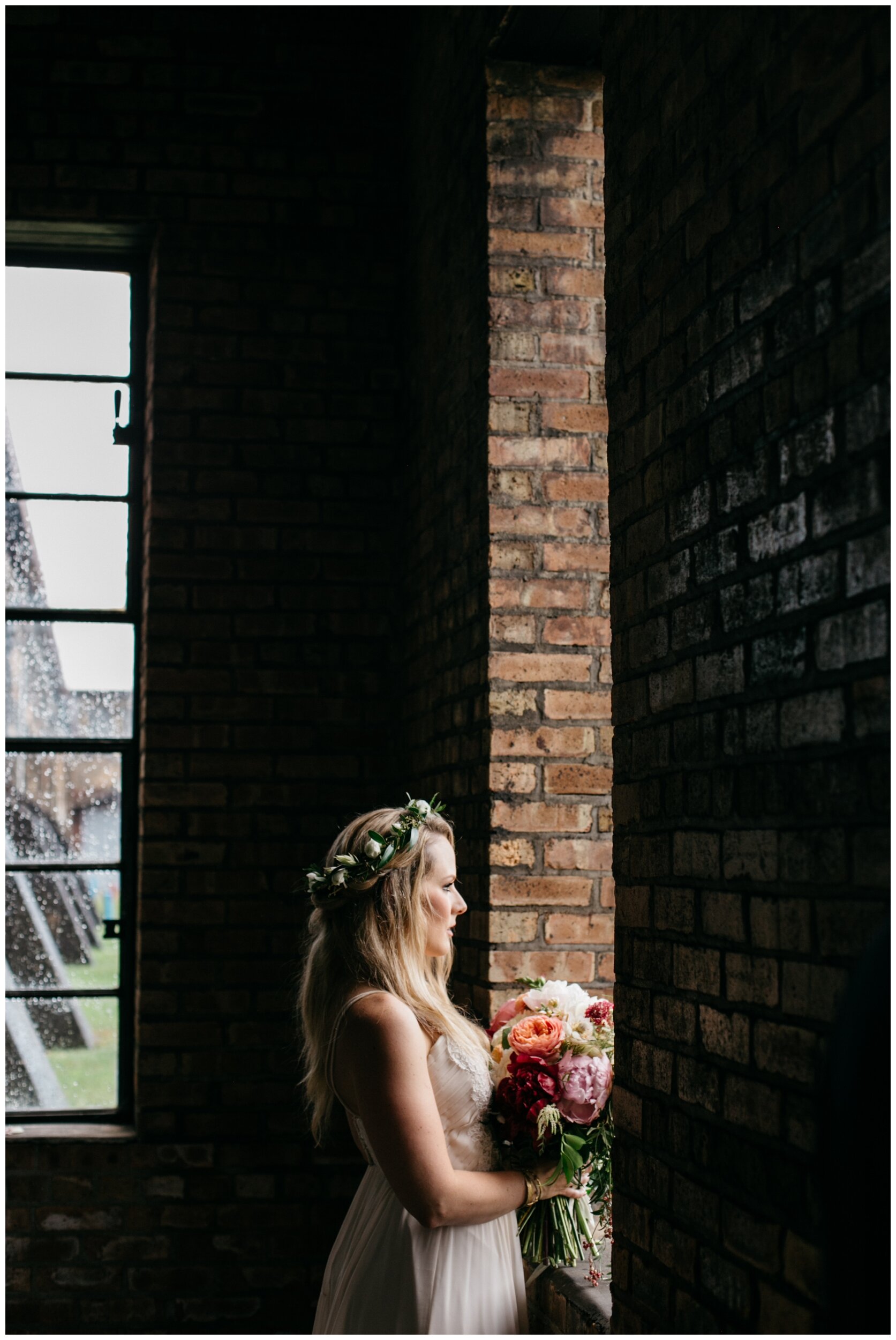 Bride standing in front of window in industrial warehouse wedding at the Northern Pacific Center in Brainerd, Minnesota