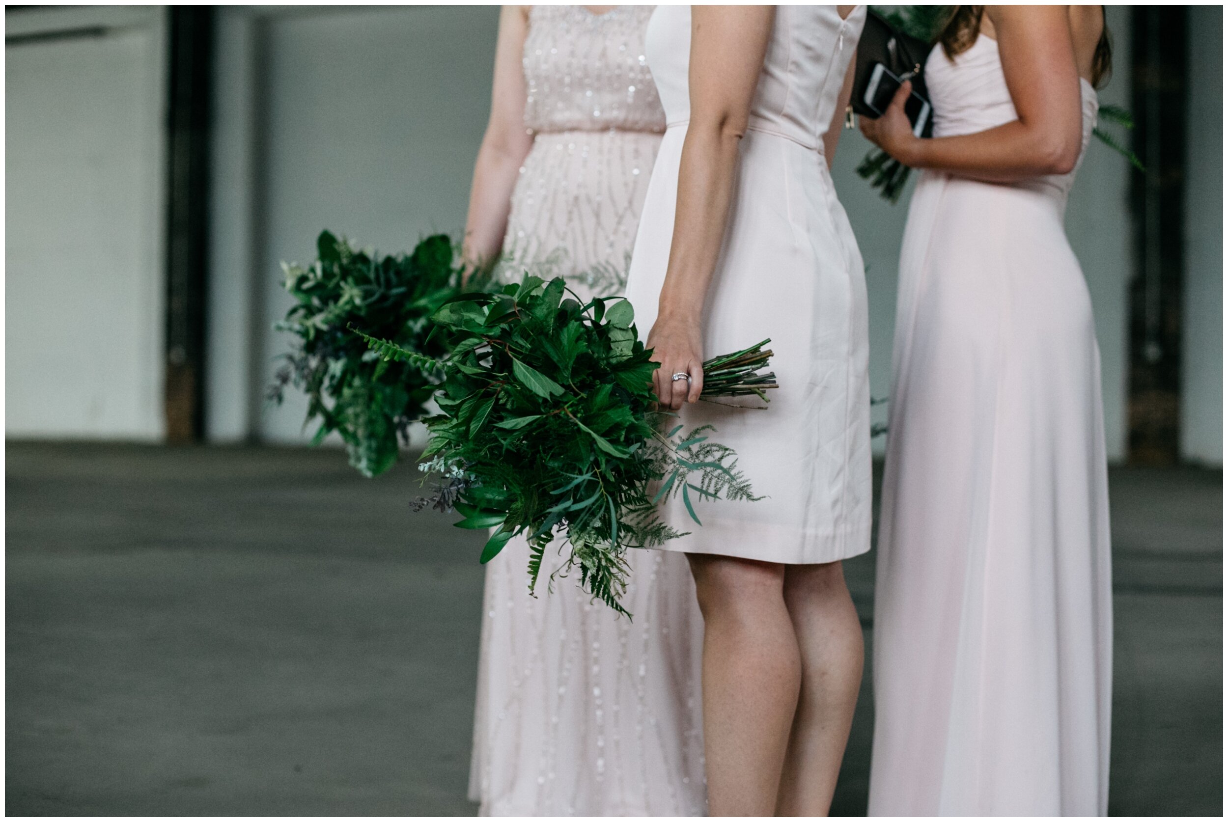 Bridesmaids wearing blush colored dresses holding fern bouquets 