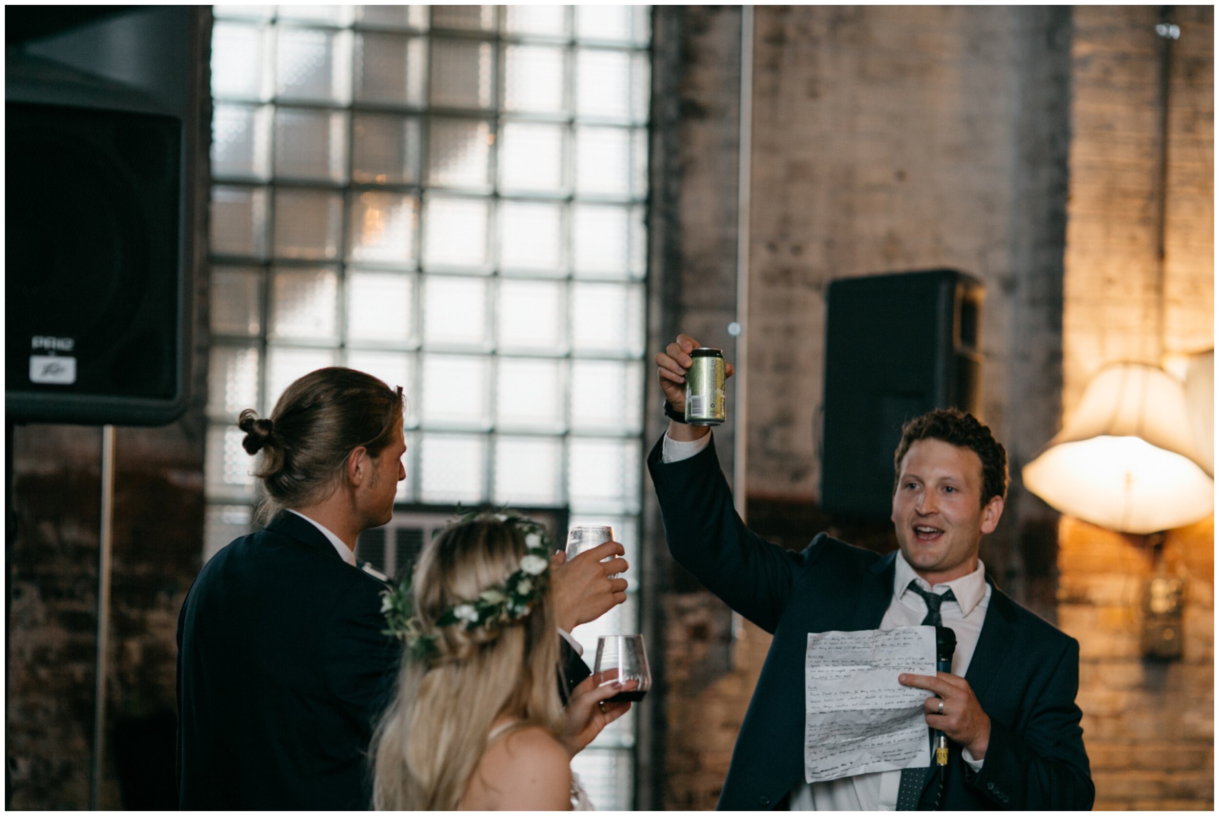 Groomsman giving toast at industrial warehouse wedding