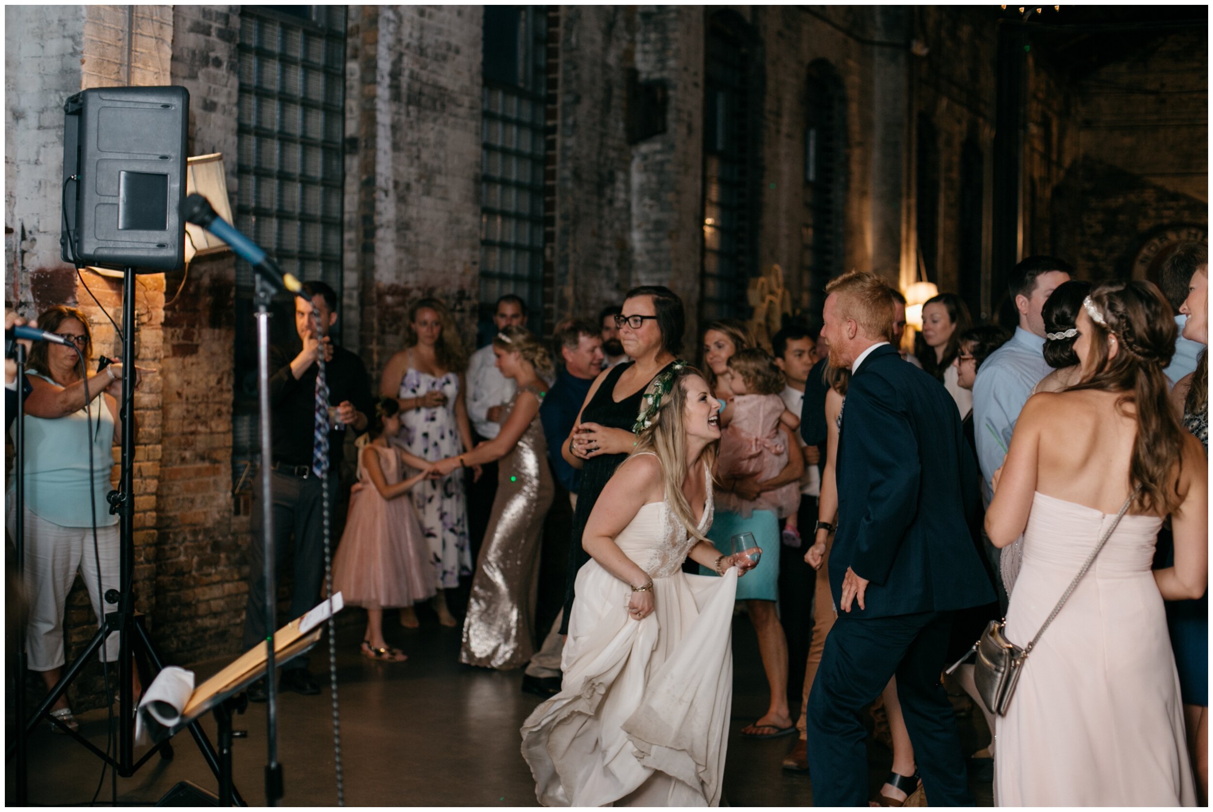Bride dancing with wedding guests in industrial warehouse wedding