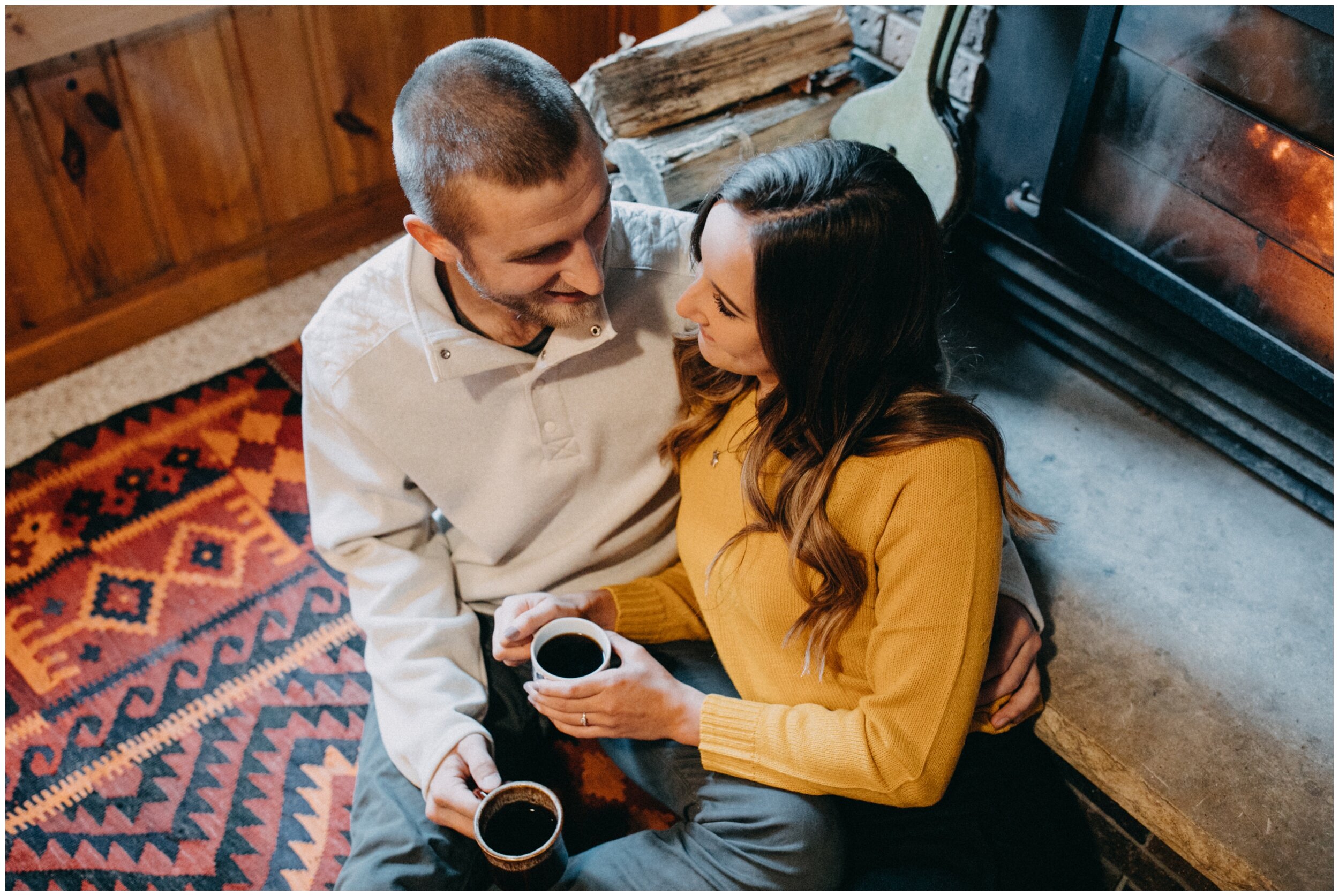 Engaged couple having coffee by the fireplace in their northern Minnesota cabin