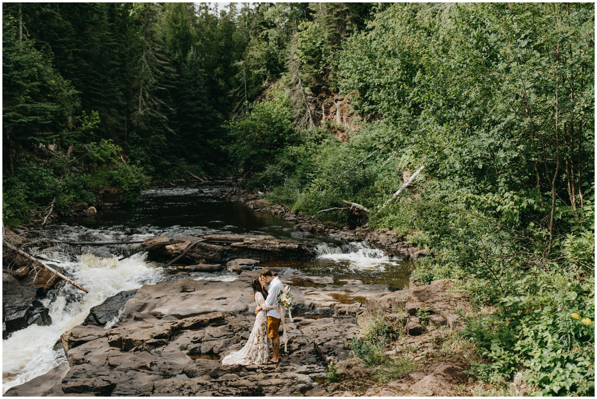 Bride and groom standing by waterfall at Lutsen resort