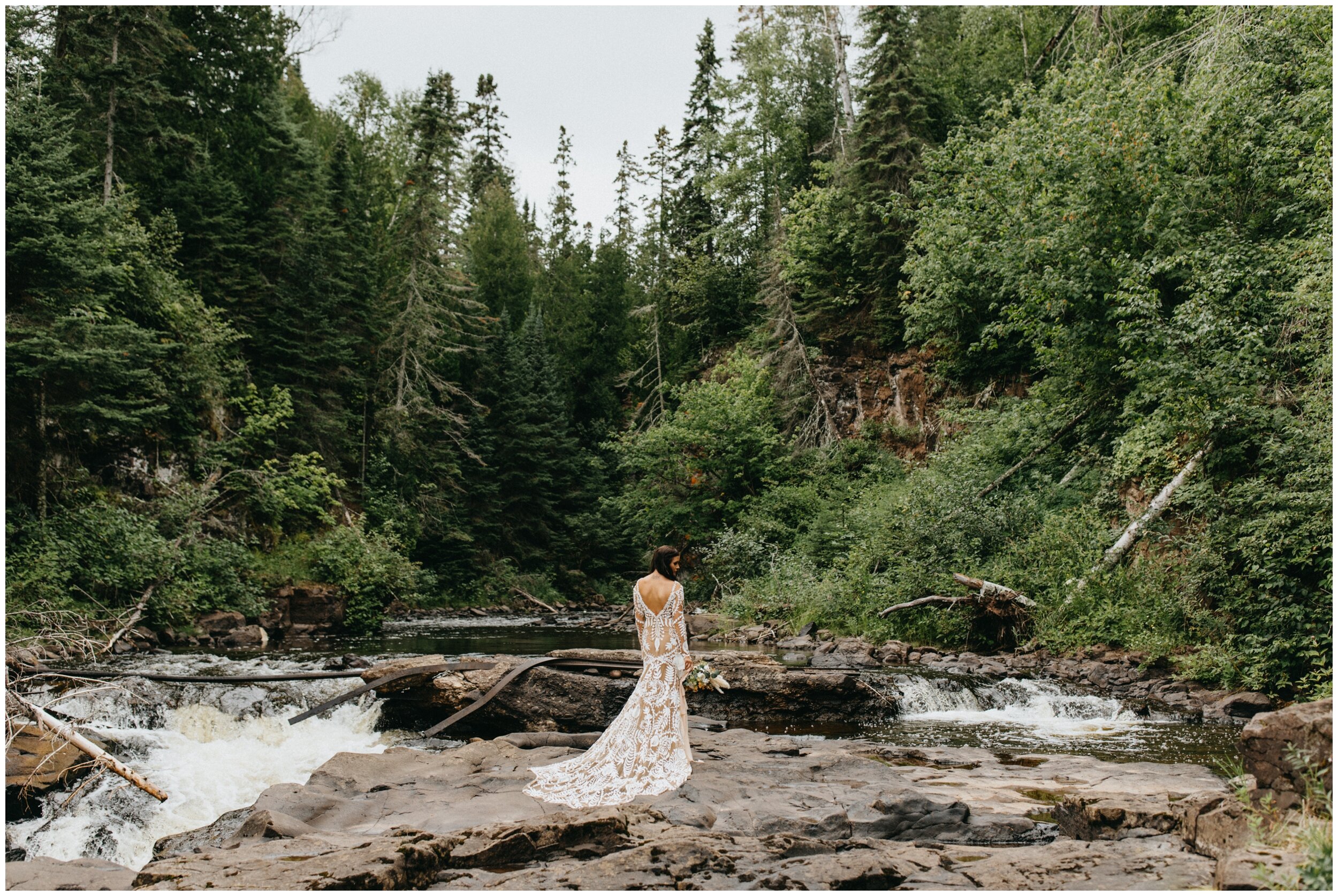 Bride standing by waterfall in the pine tree forest at Lutsen resort on Lake Superior