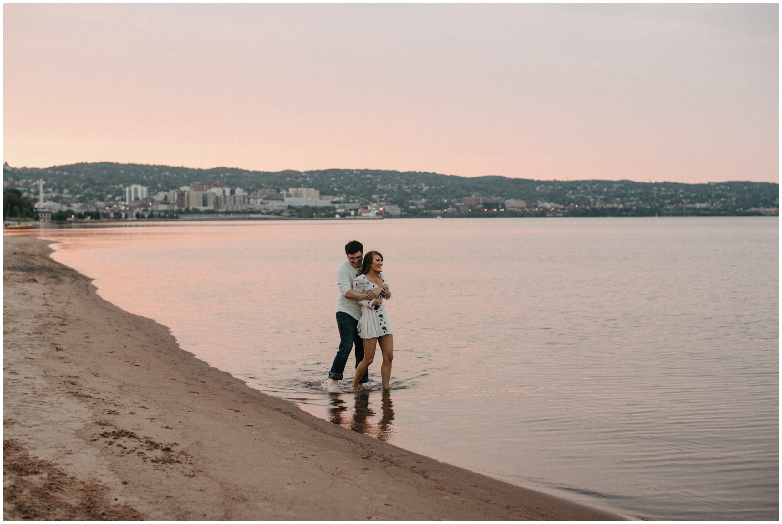 Couple playing in Lake Superior during Park Point Beach engagement session in Duluth, Minnesota