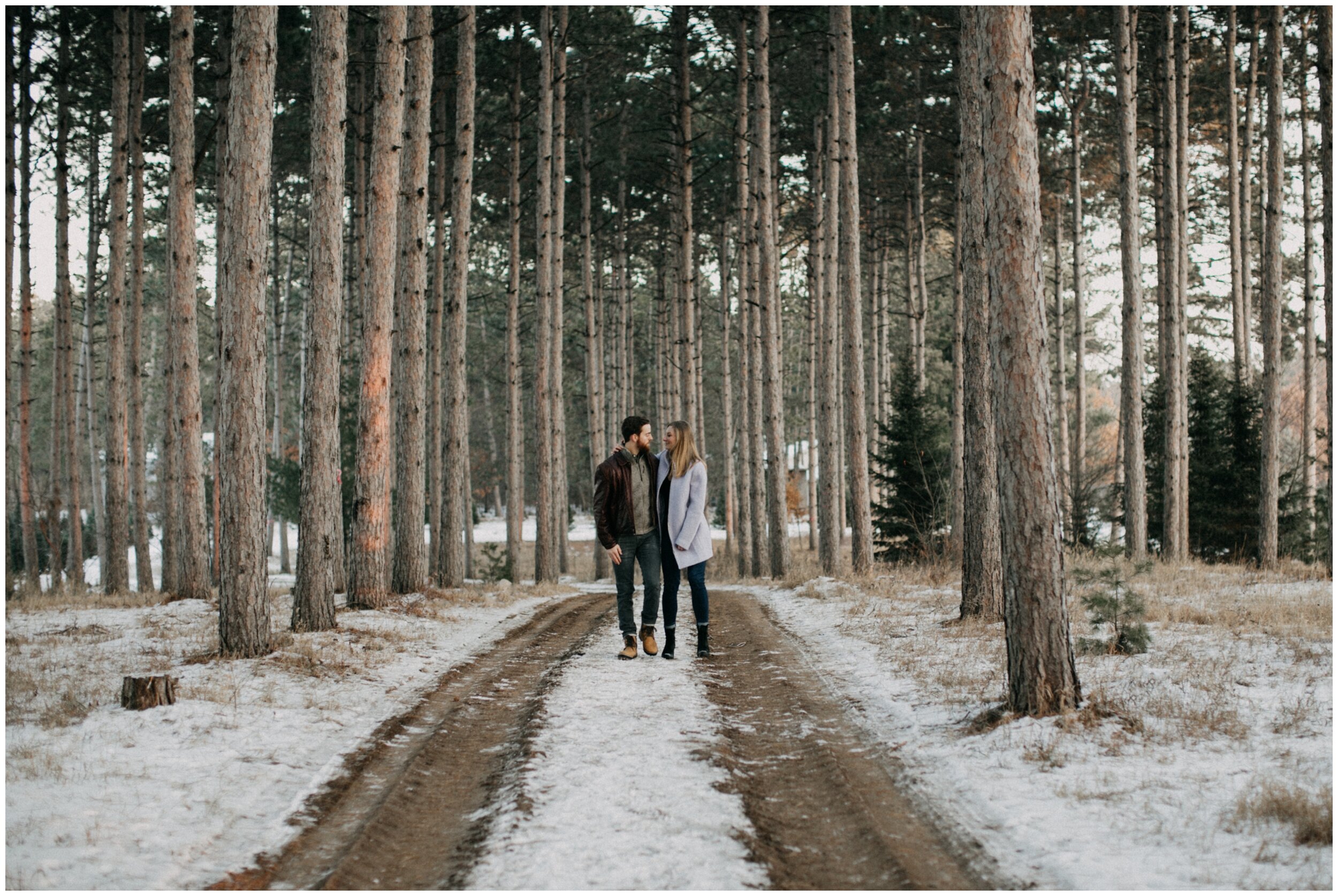 Couple walking through pine tree forest in Minnesota