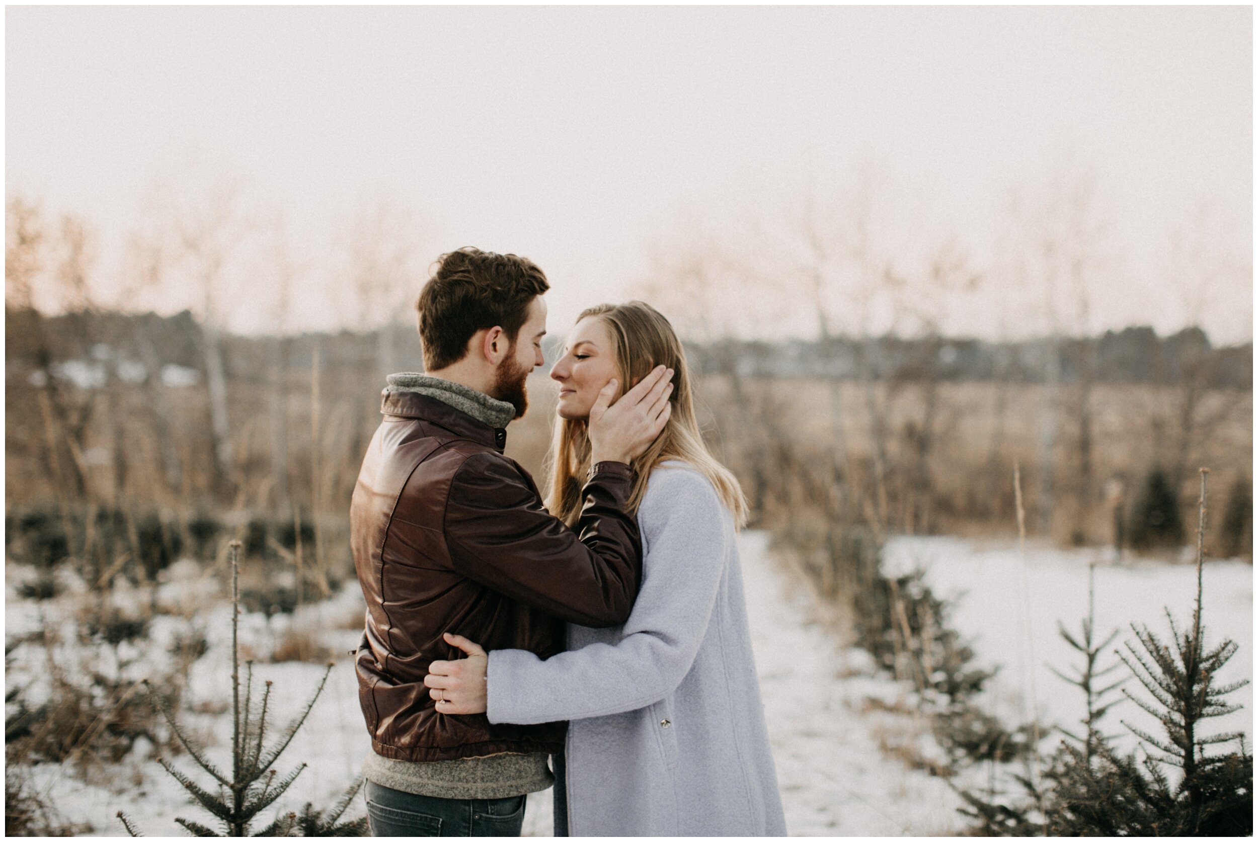 Boyfriend touching girlfriends face during engagement session at Minnesota Christmas tree farm