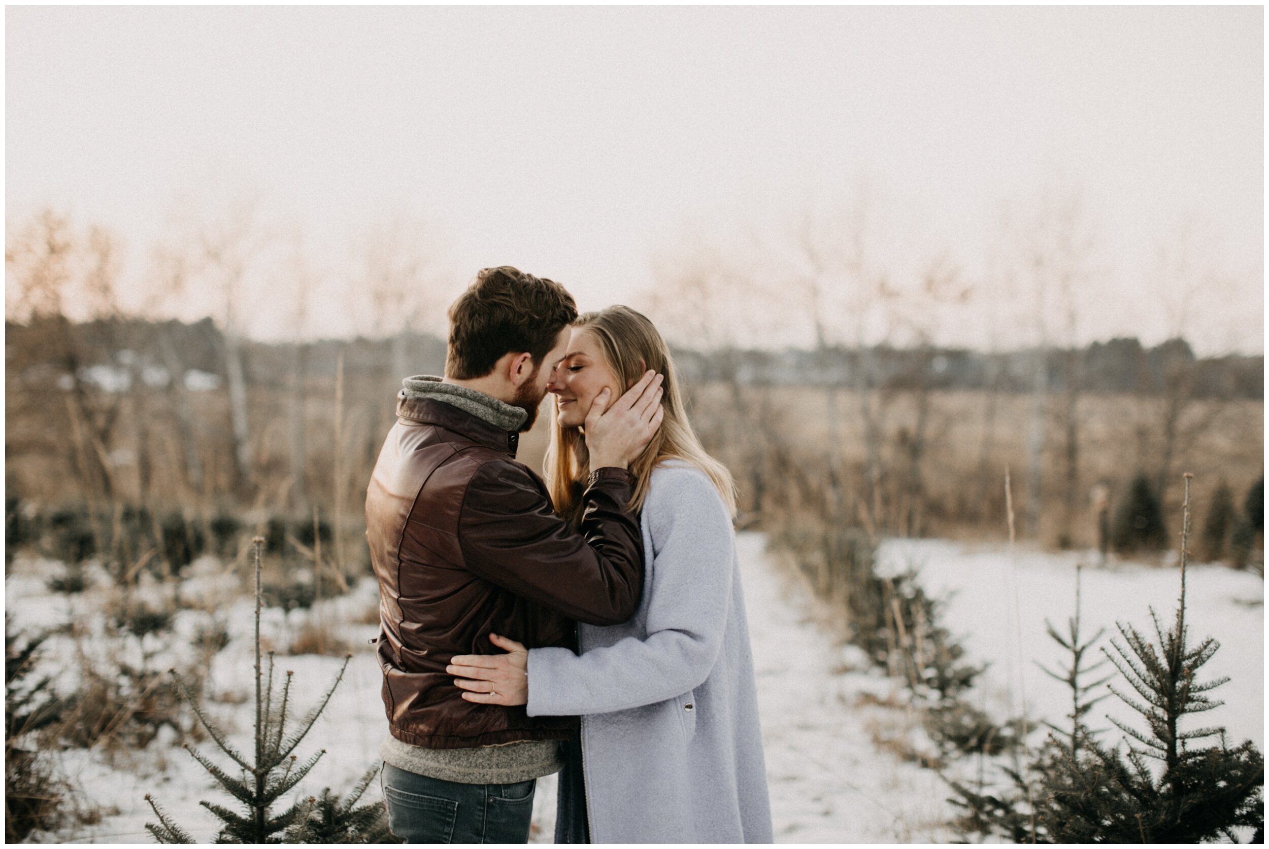 Couple hugging and touching noses during engagement session at Minnesota Christmas tree farm