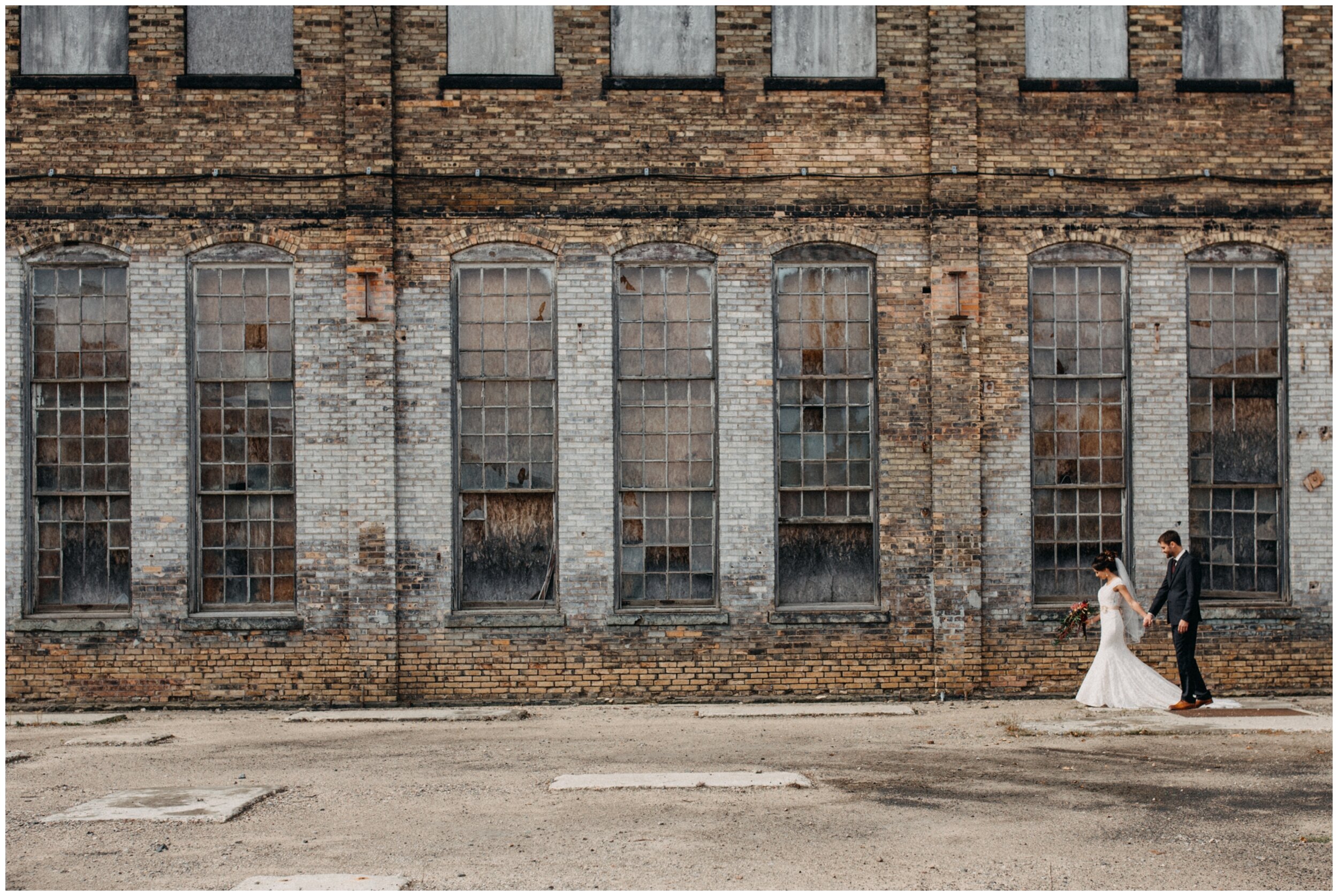 Bride and groom walking in front of industrial building at the Northern Pacific Center in Brainerd, Minnesota