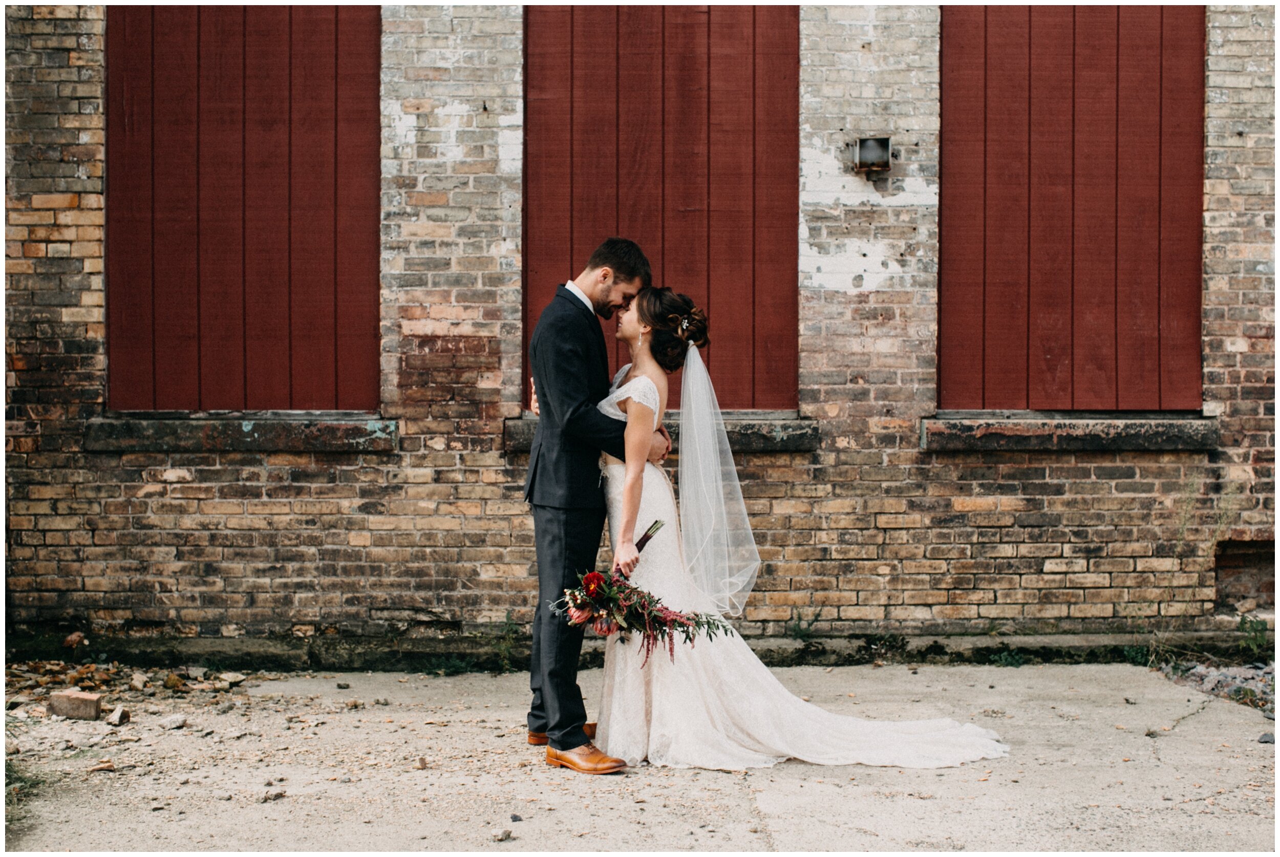 Bride and groom standing in front warehouse at modern, industrial Northern Pacific center wedding 