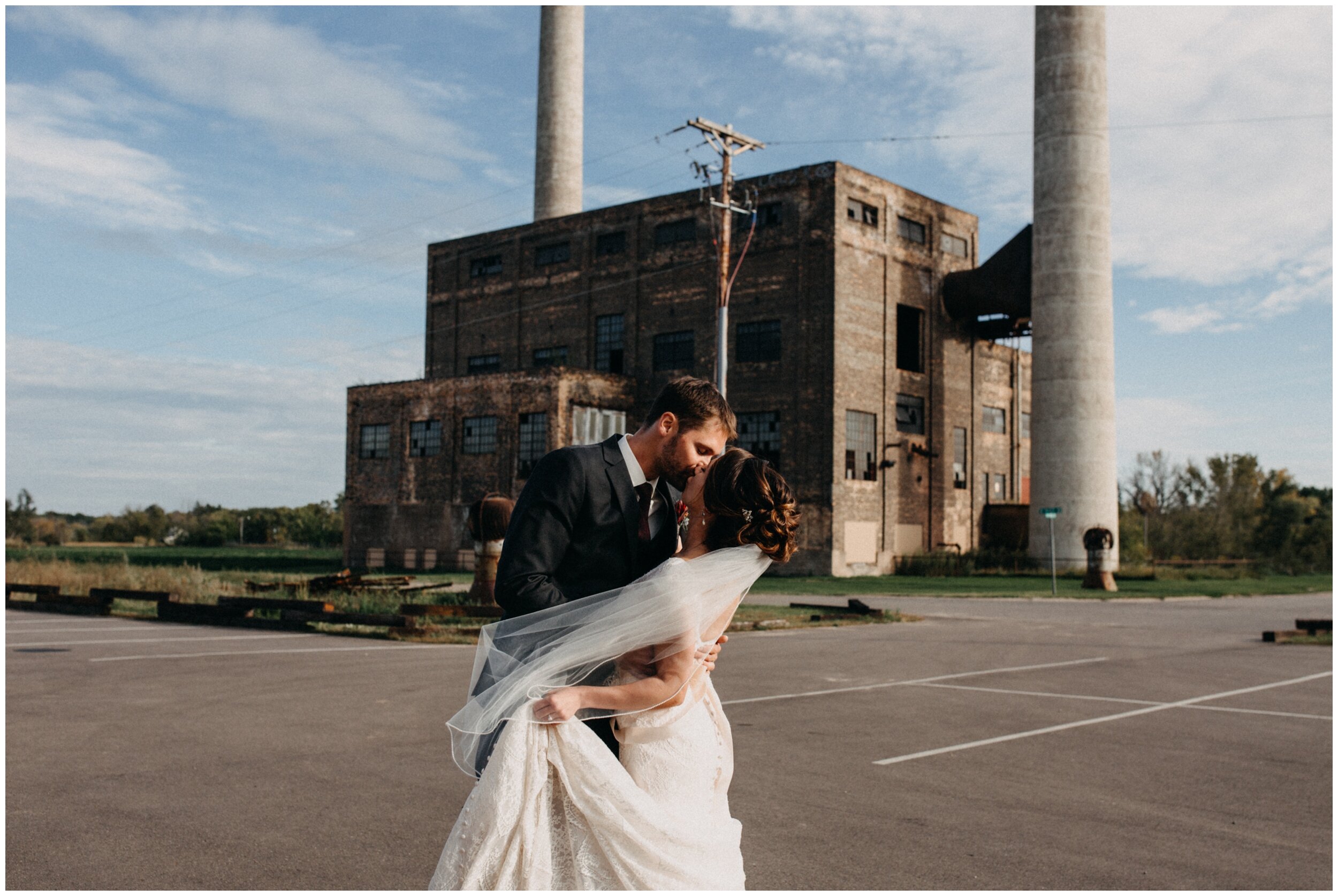 Bride and groom kissing in front of power plant industrial building at the Northern Pacific Center in Brainerd, Minnesota
