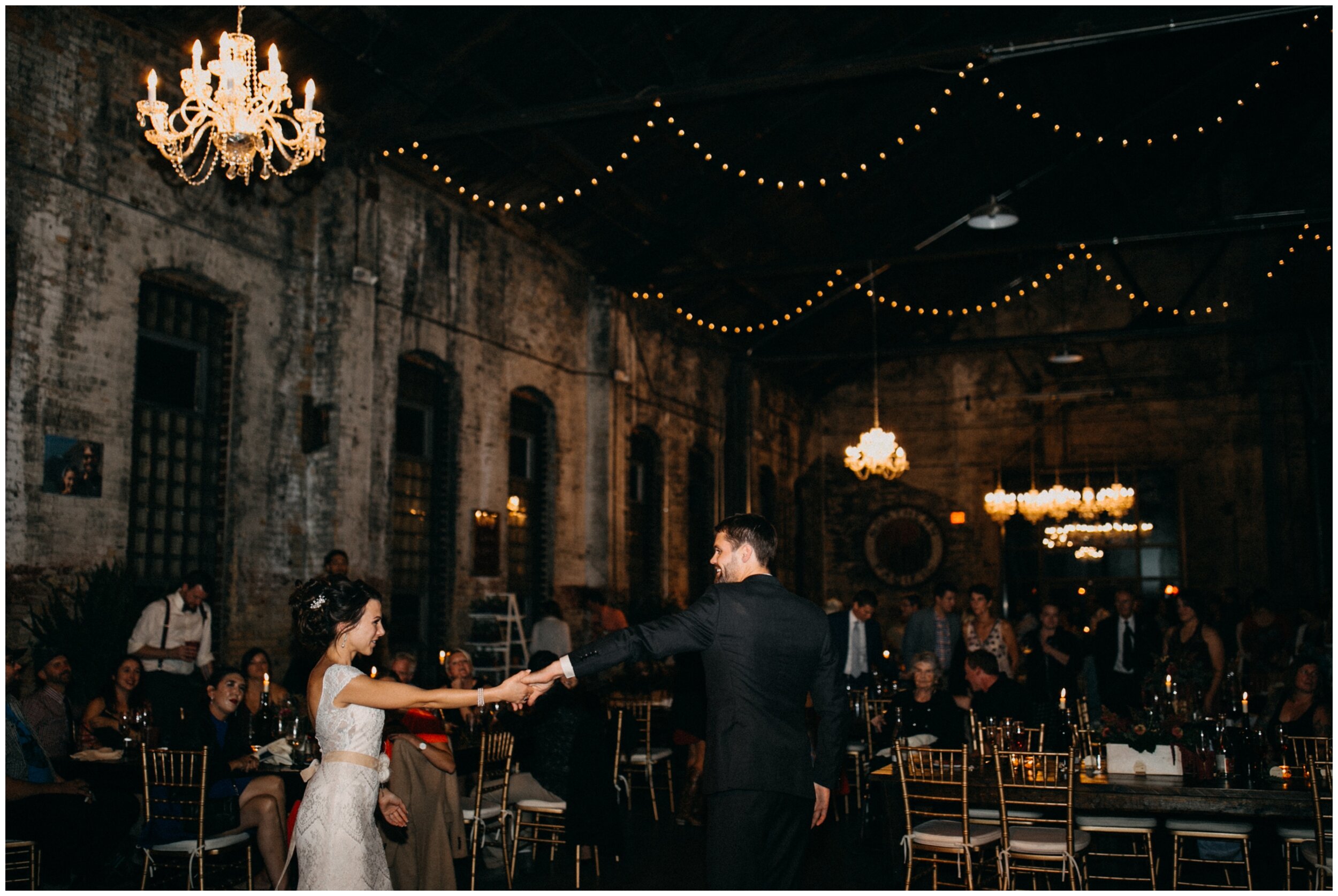 Bride and groom dancing with chandelier and string lights hanging overhead at the Northern Pacific Center in Brainerd, Minnesota