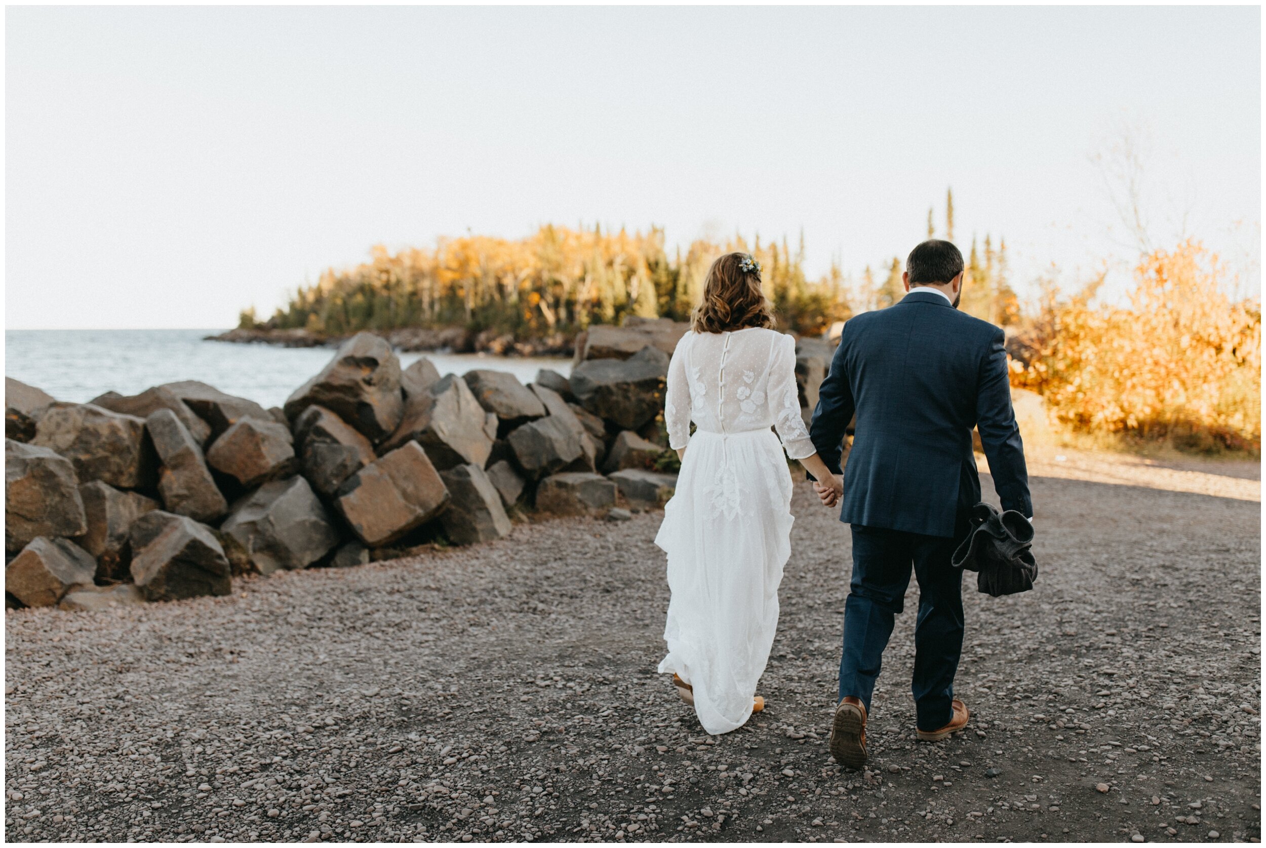 Bride and groom walking to wedding ceremony in the woods on Artists' Point in Grand Marais, Minnesota
