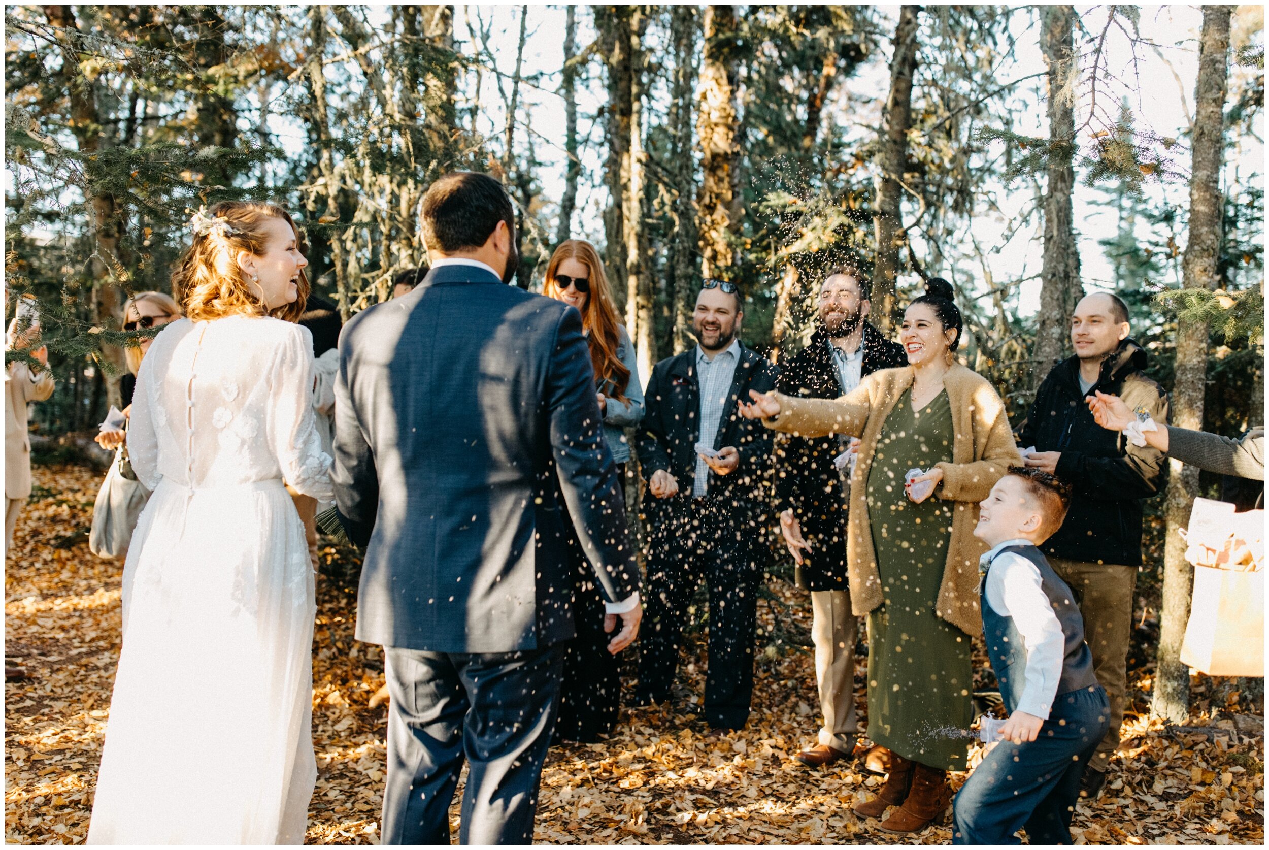 Wedding guests throwing lavender confetti at the bride and groom after intimate wedding ceremony in the woods