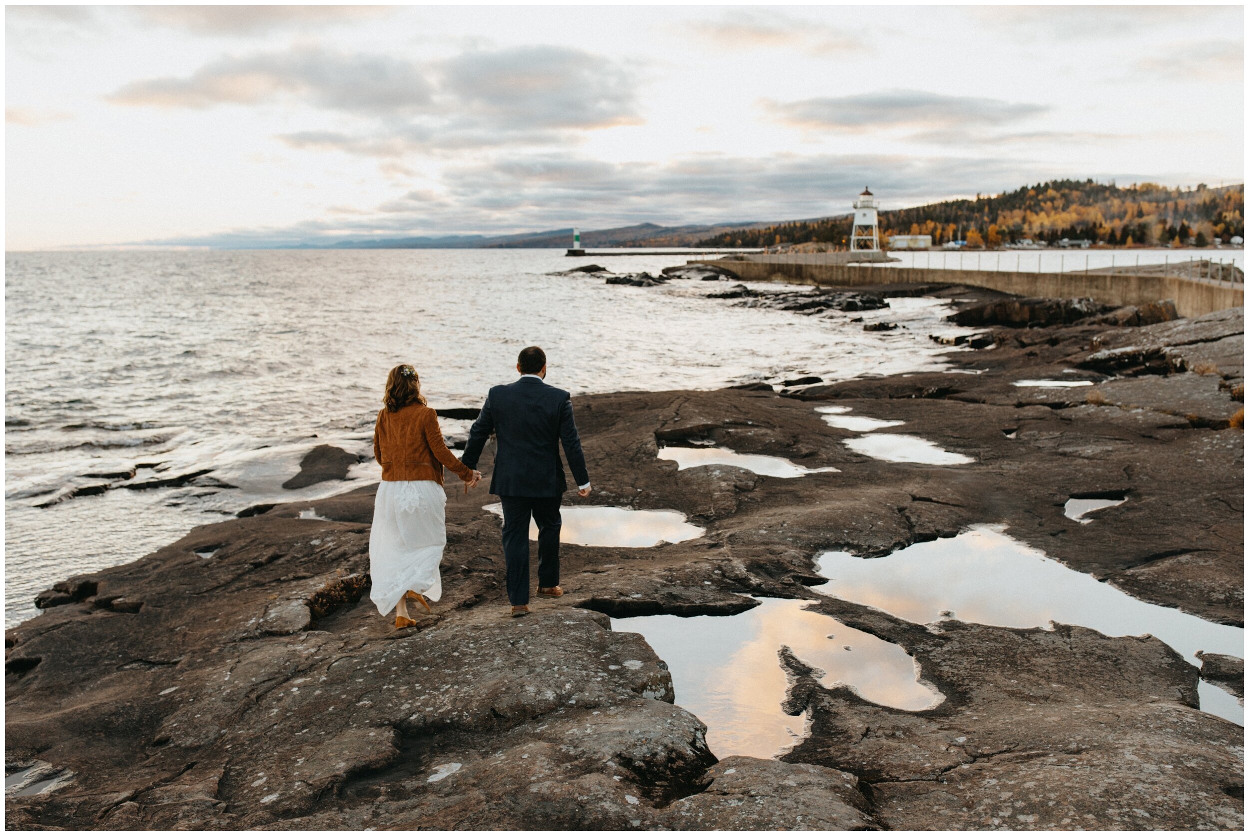 Bride and groom walking in rocky shore of Artists' Point during Grand Marais Minnesota wedding