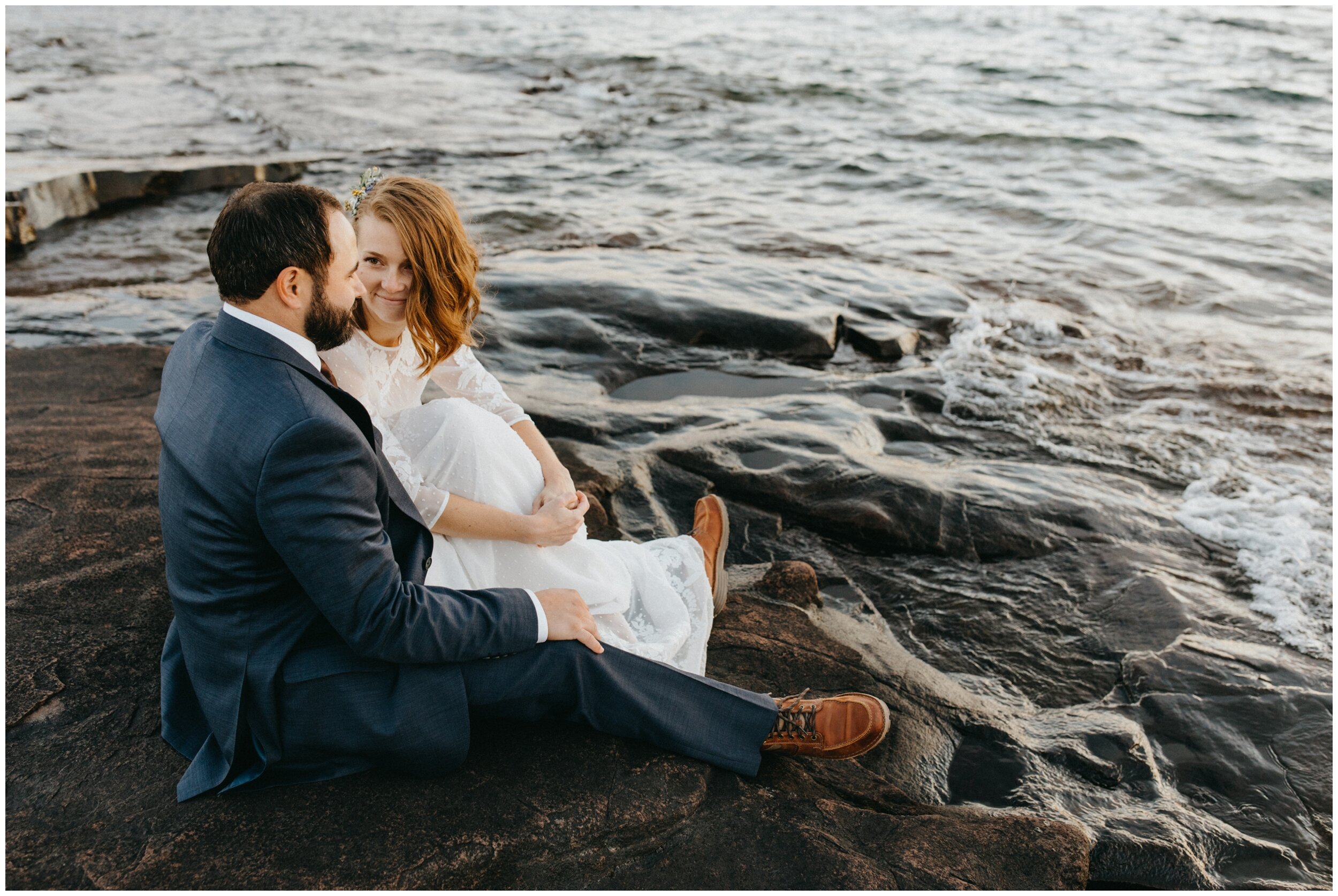 Bride and groom sitting on the north shore on Artists' Point in Grand Marais, Minnesota