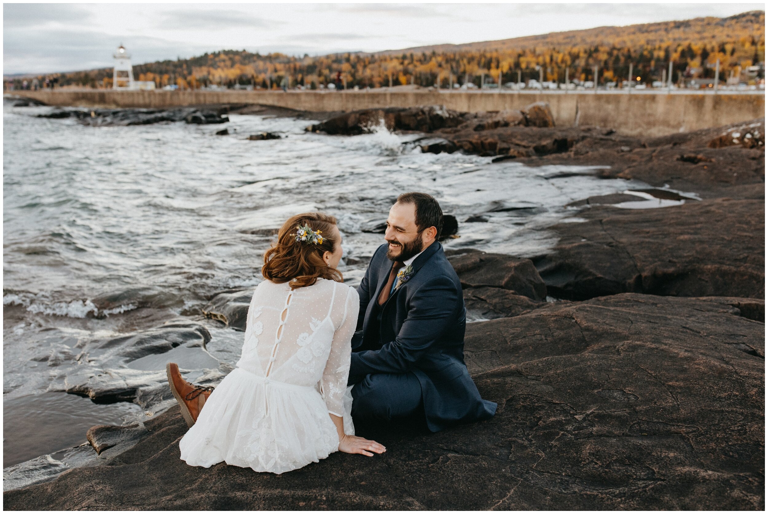 Bride and groom sitting on the rocky north shore during sunset after Grand Marais, Minnesota wedding