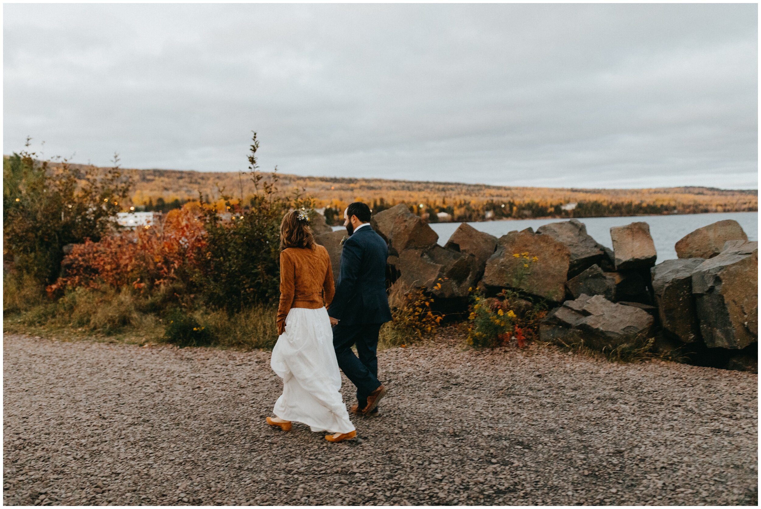 Bride and groom walking along Lake Superior on Minnesota fall wedding in Grand Marais, MN