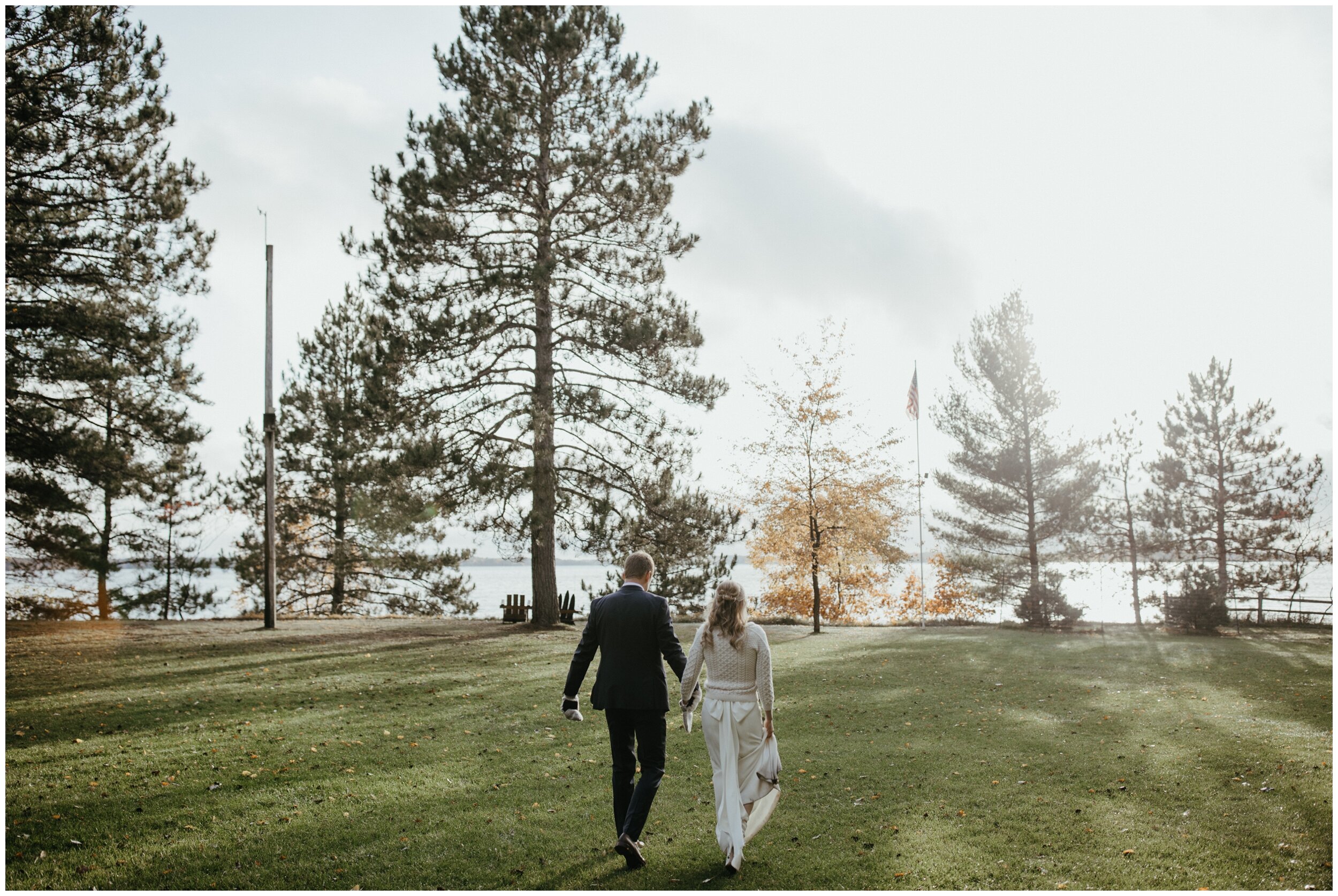 Bride and groom walking among the pines at Minnesota fall wedding on Crosslake