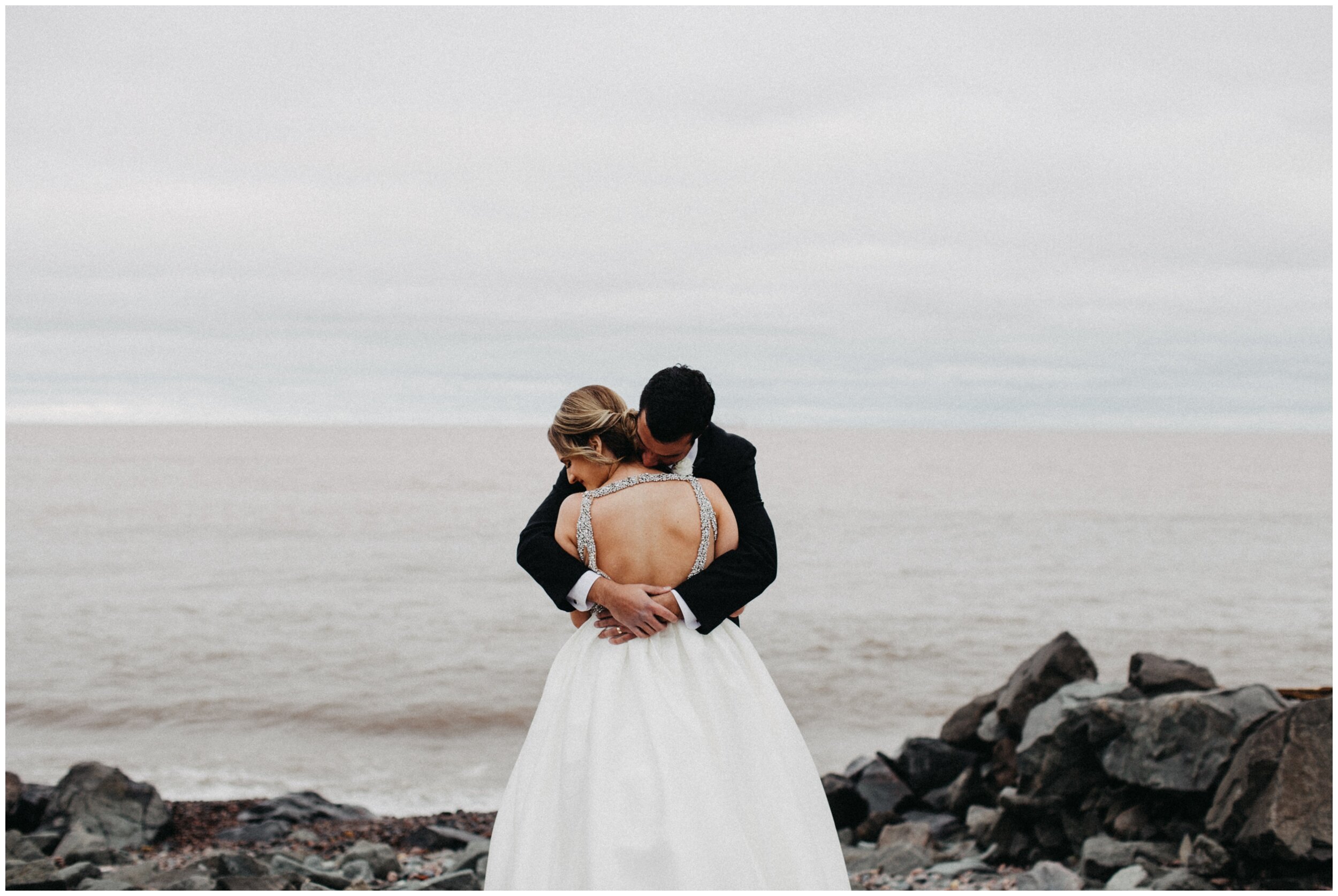 Bride and groom standing on rocks overlooking lake superior in Duluth, Minnesota