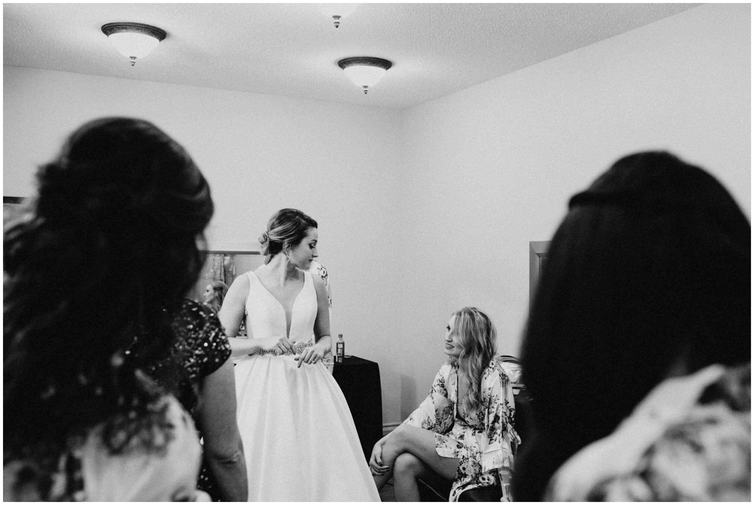 Bridesmaid helping bride into wedding dress at the Greysolon in Duluth