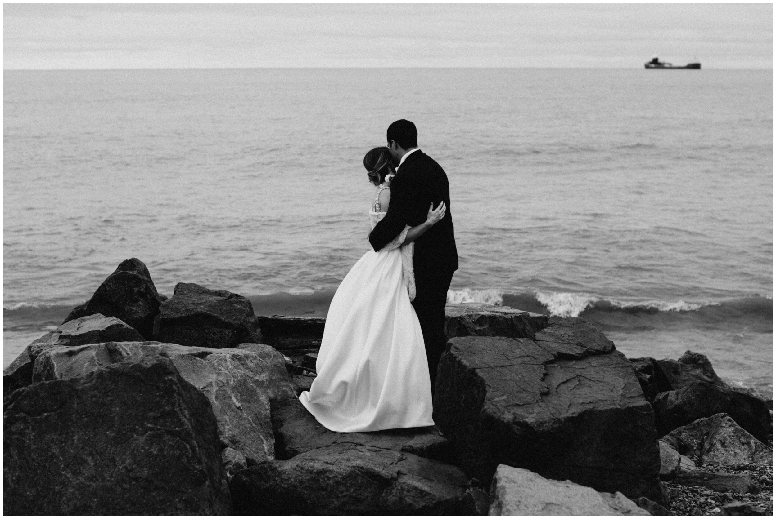 Bride and groom standing on rocks looking out at lake superior in Duluth, MNlake superior i