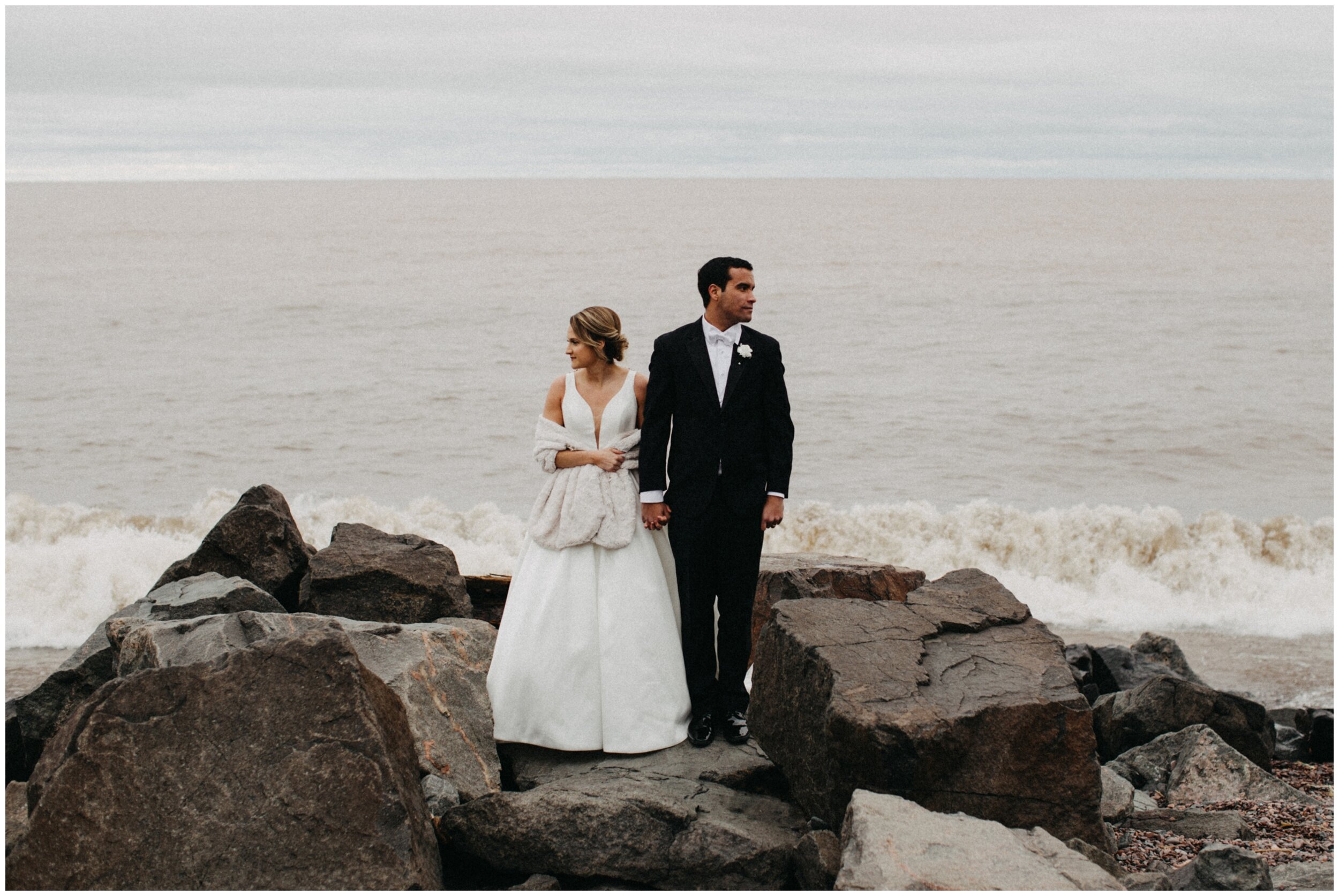 Bride standing on lake superior rocky beach in Duluth, Minnesota