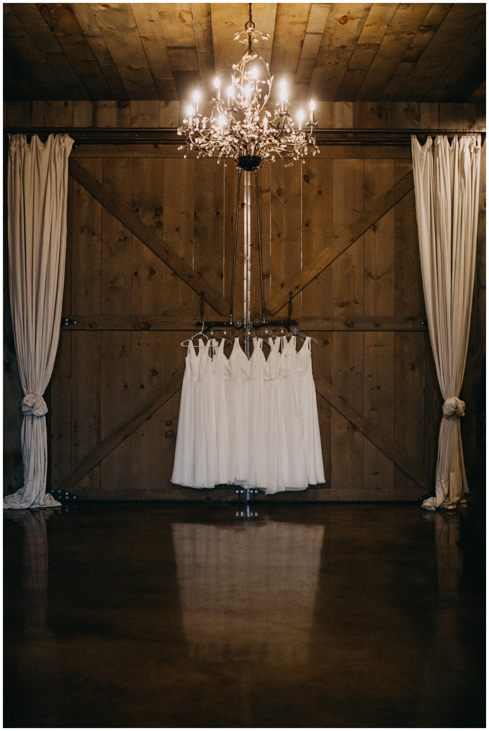 All white bridesmaid dresses hanging in barn wedding venue at Creekside Farm