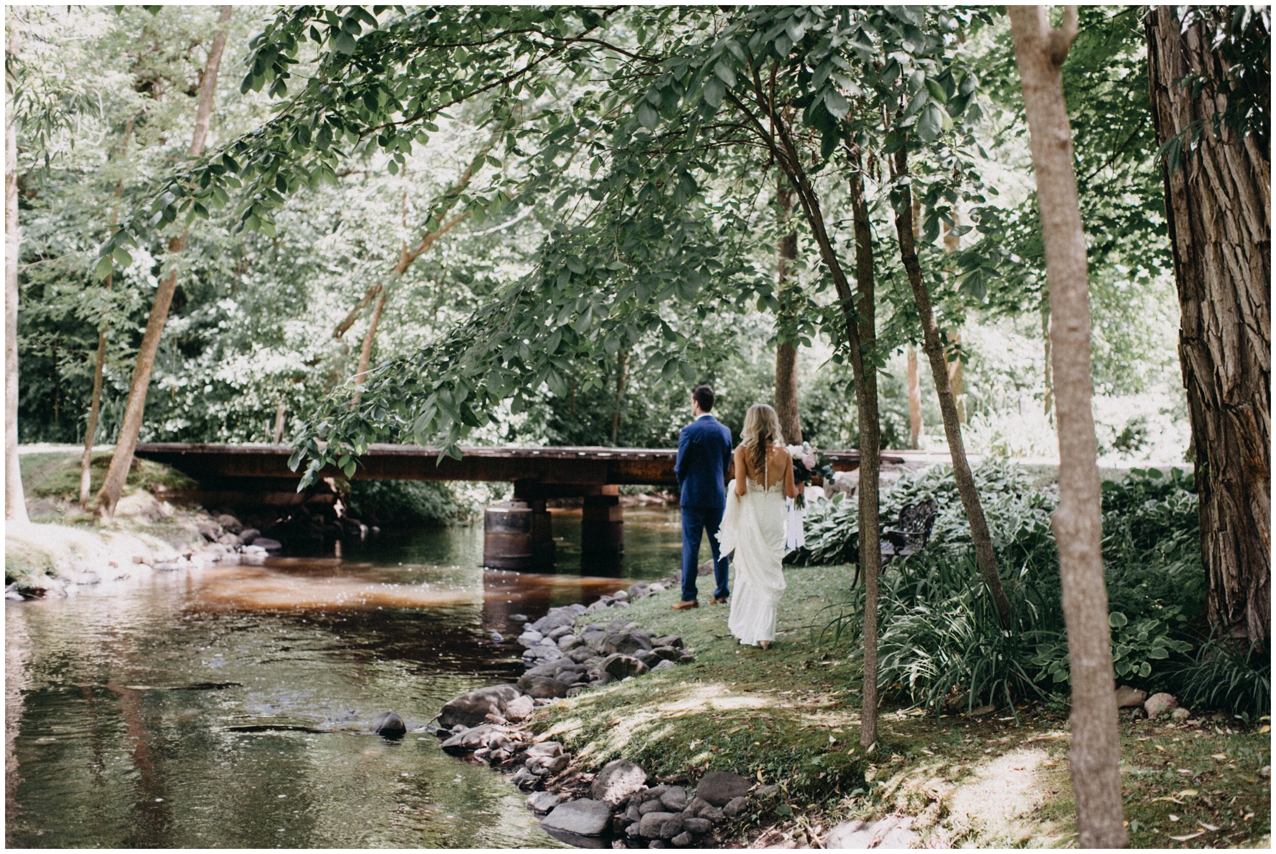 Bride and groom first look alongside creek at Minnesota farm wedding venue