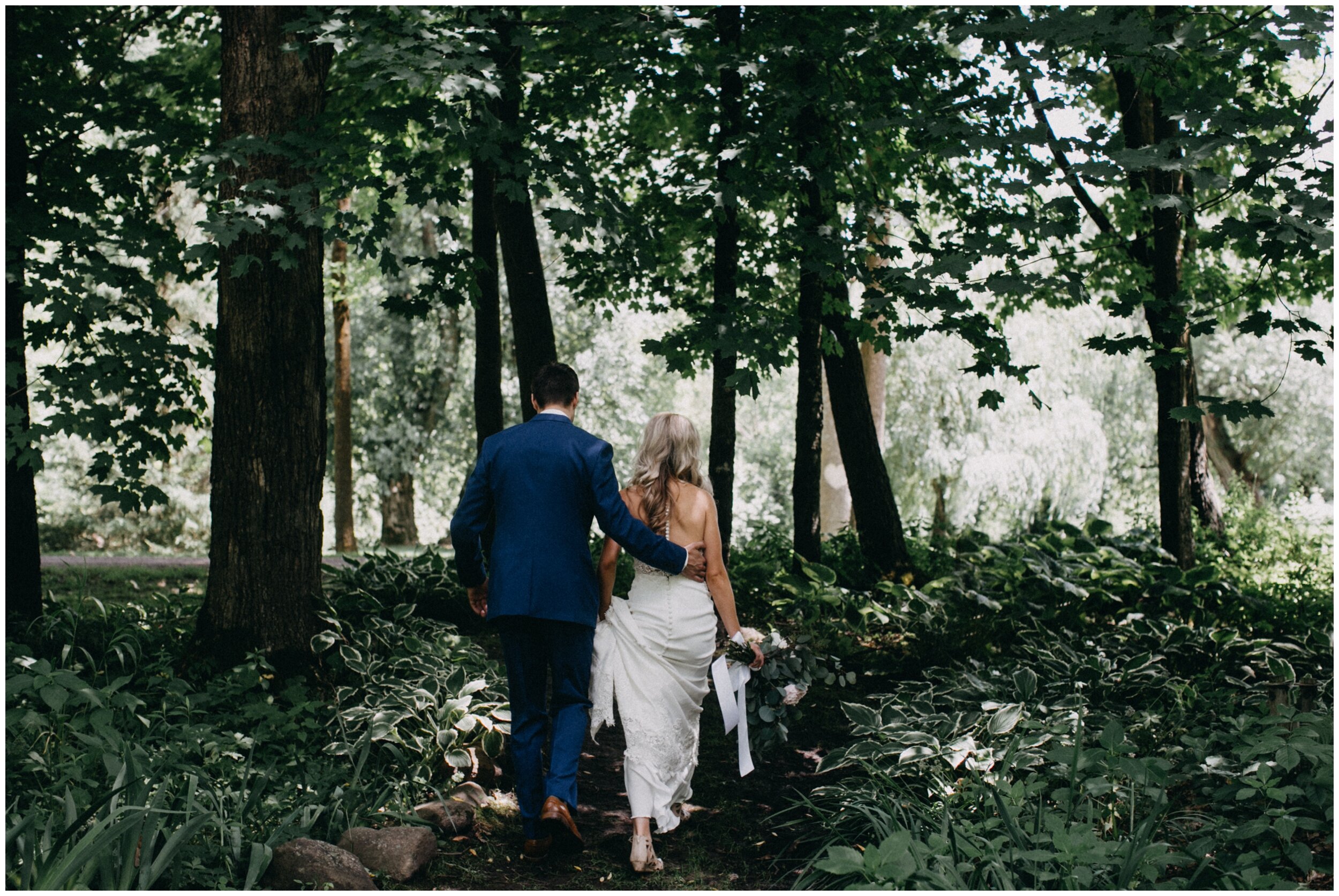 Bride and groom walking in woods at Creekside farm wedding venue