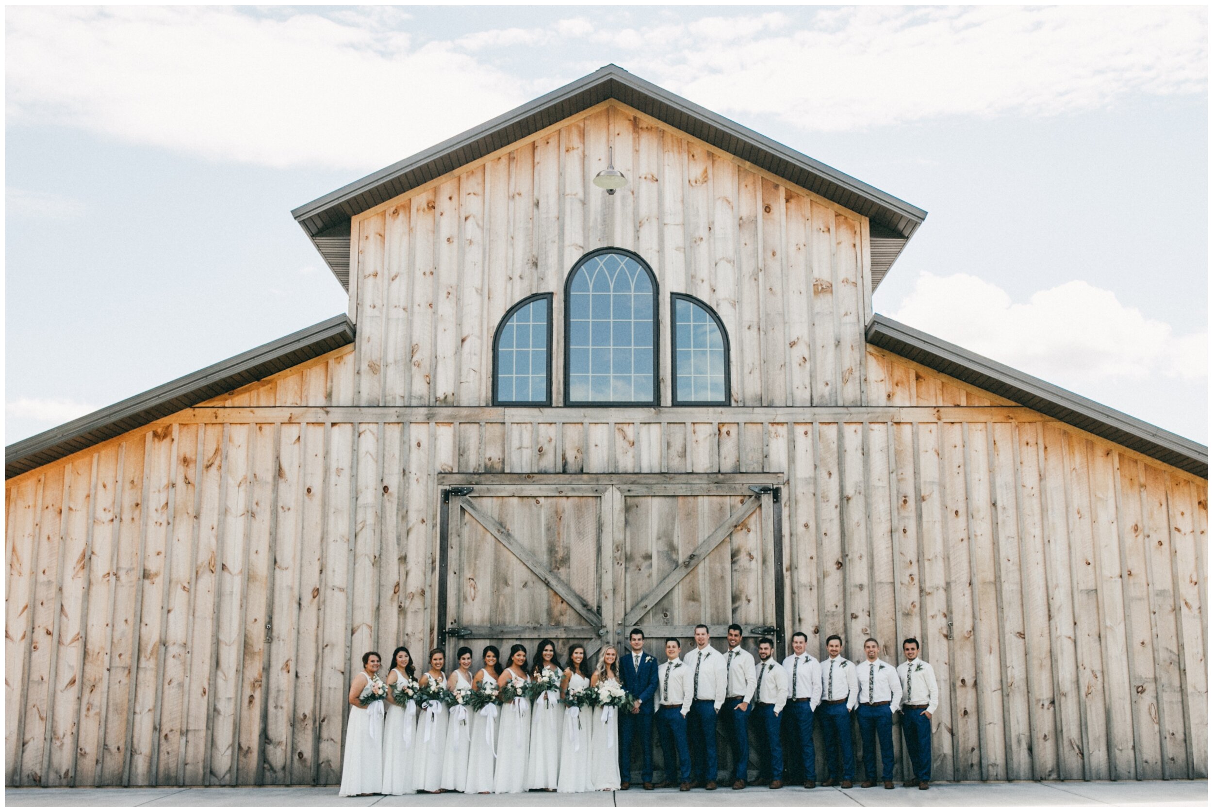 Wedding party standing outside barn wedding venue at Creekside Farm in Rush City Minnesota