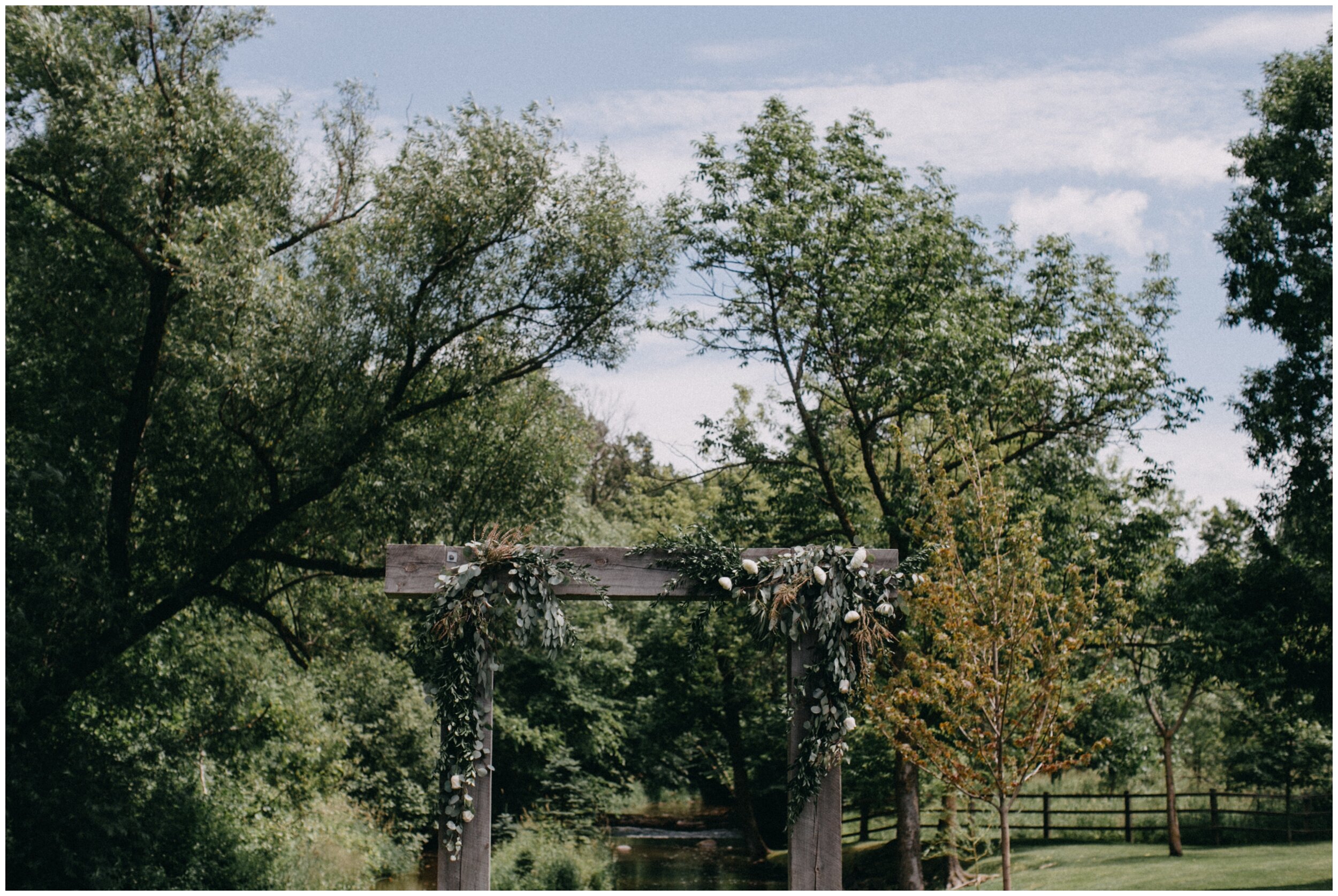 Wooden wedding ceremony arch decorated with roses and eucalyptus at Creekside Farm wedding ceremony