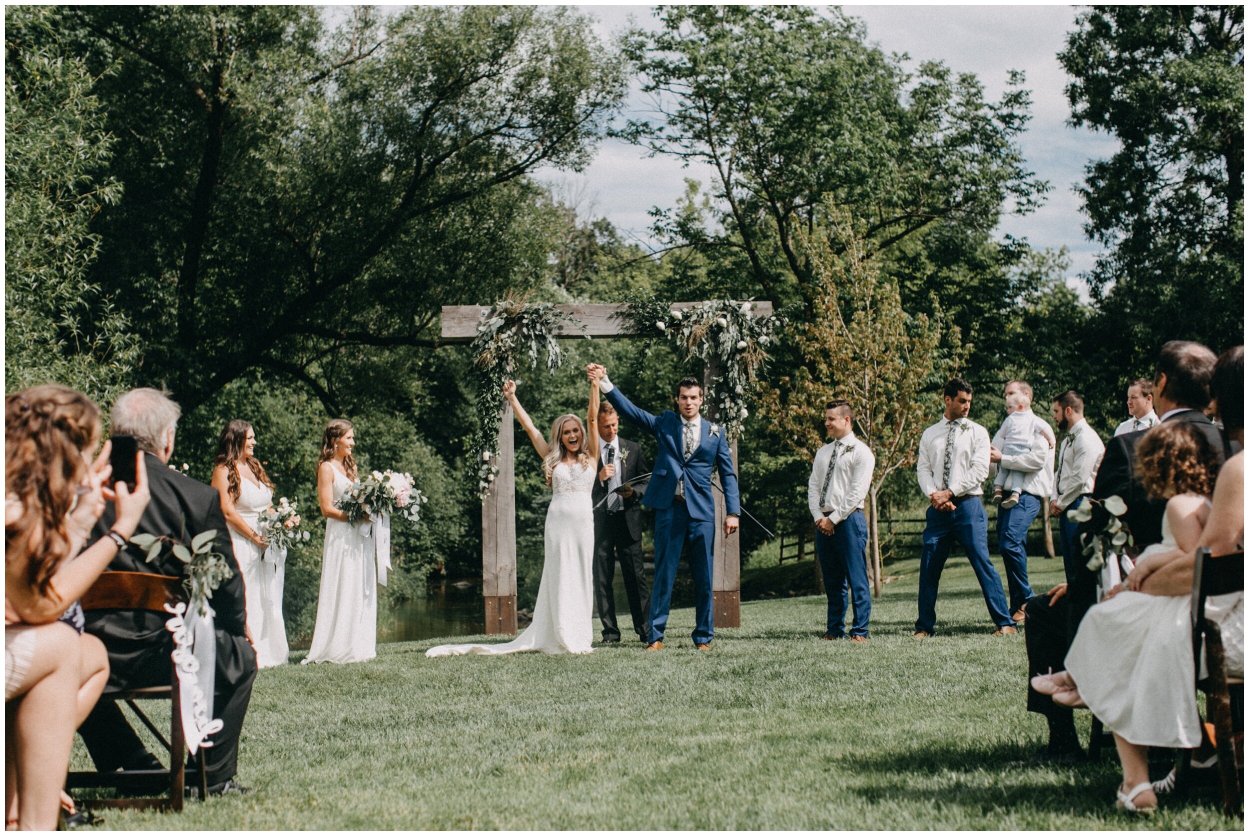 Bride and groom cheering after outdoor Minnesota barn wedding ceremony
