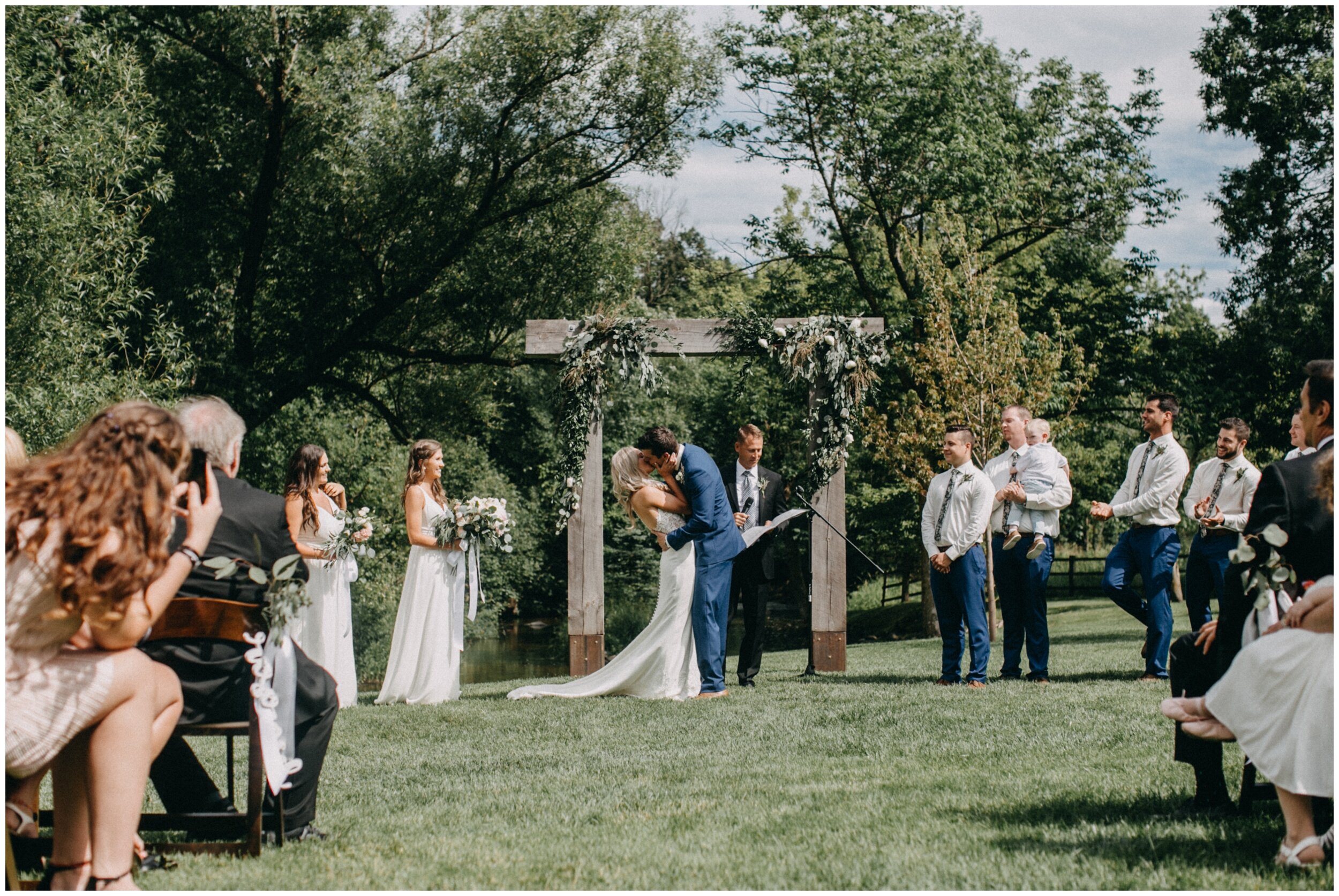 Bride and groom first kiss during romantic Minnesota barn wedding ceremony