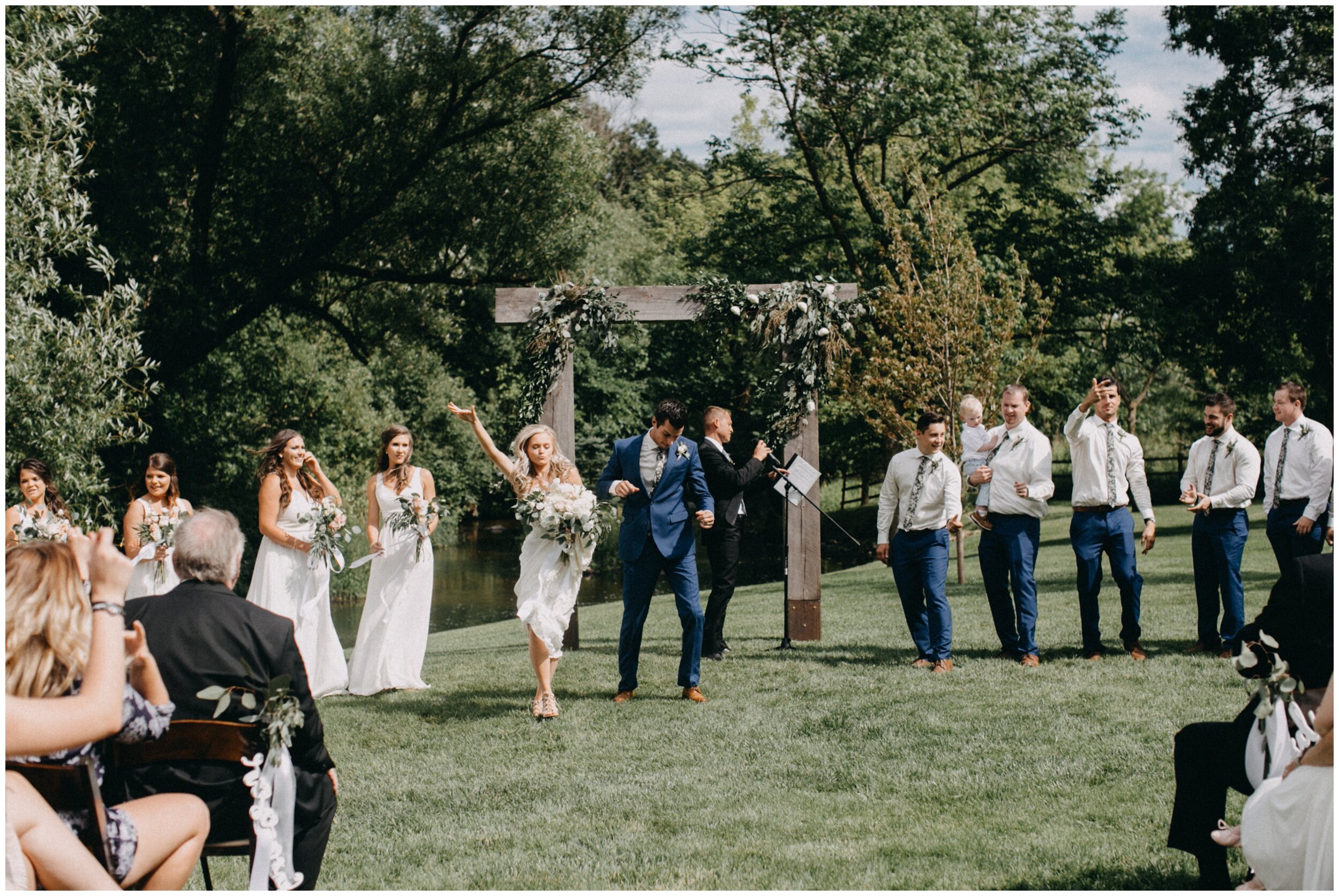 Bride and groom dancing down aisle after outdoor Minnesota barn wedding ceremony