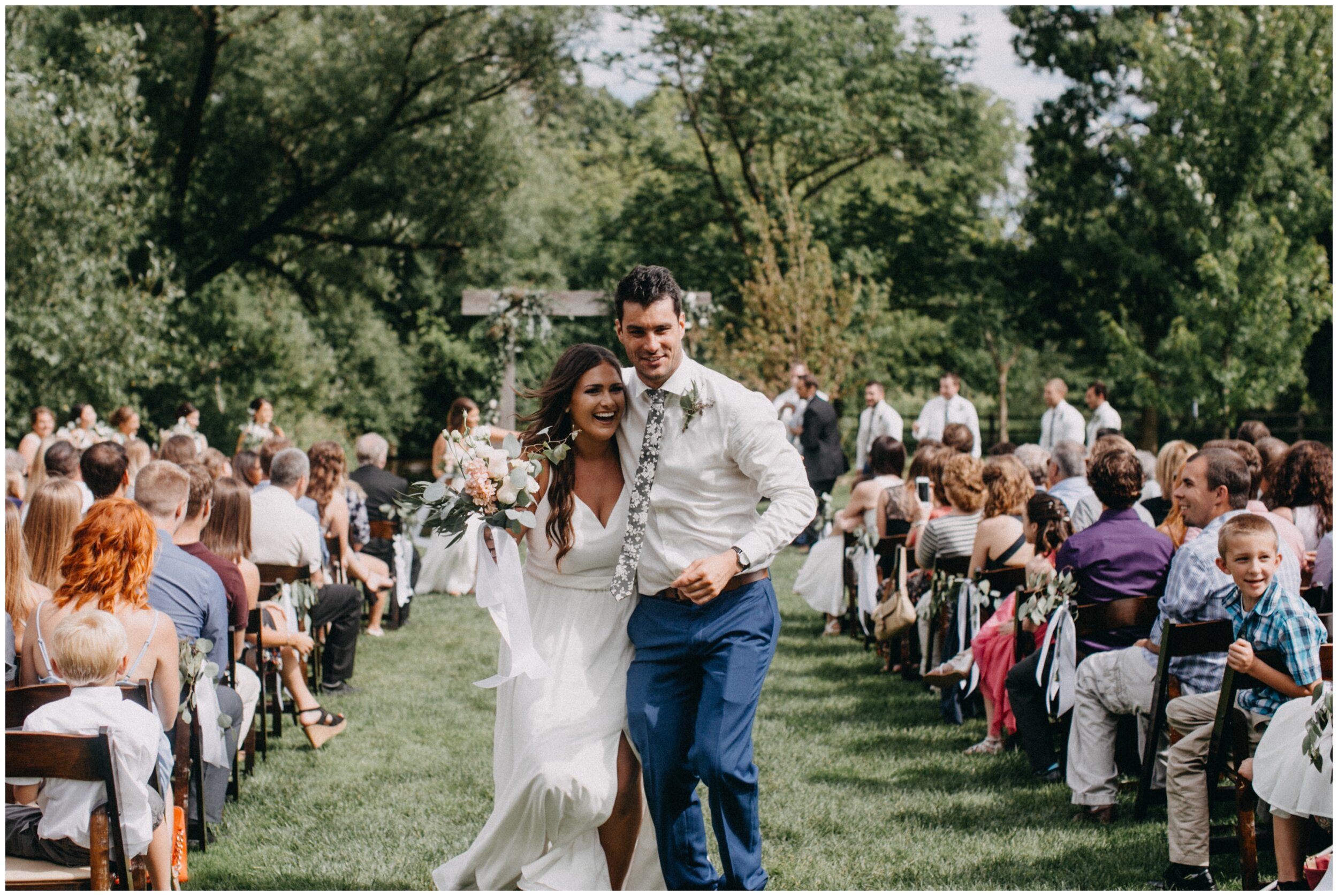 Bridesmaid and groomsman excitedly walk down aisle after outdoor barn wedding ceremony in Minnesota