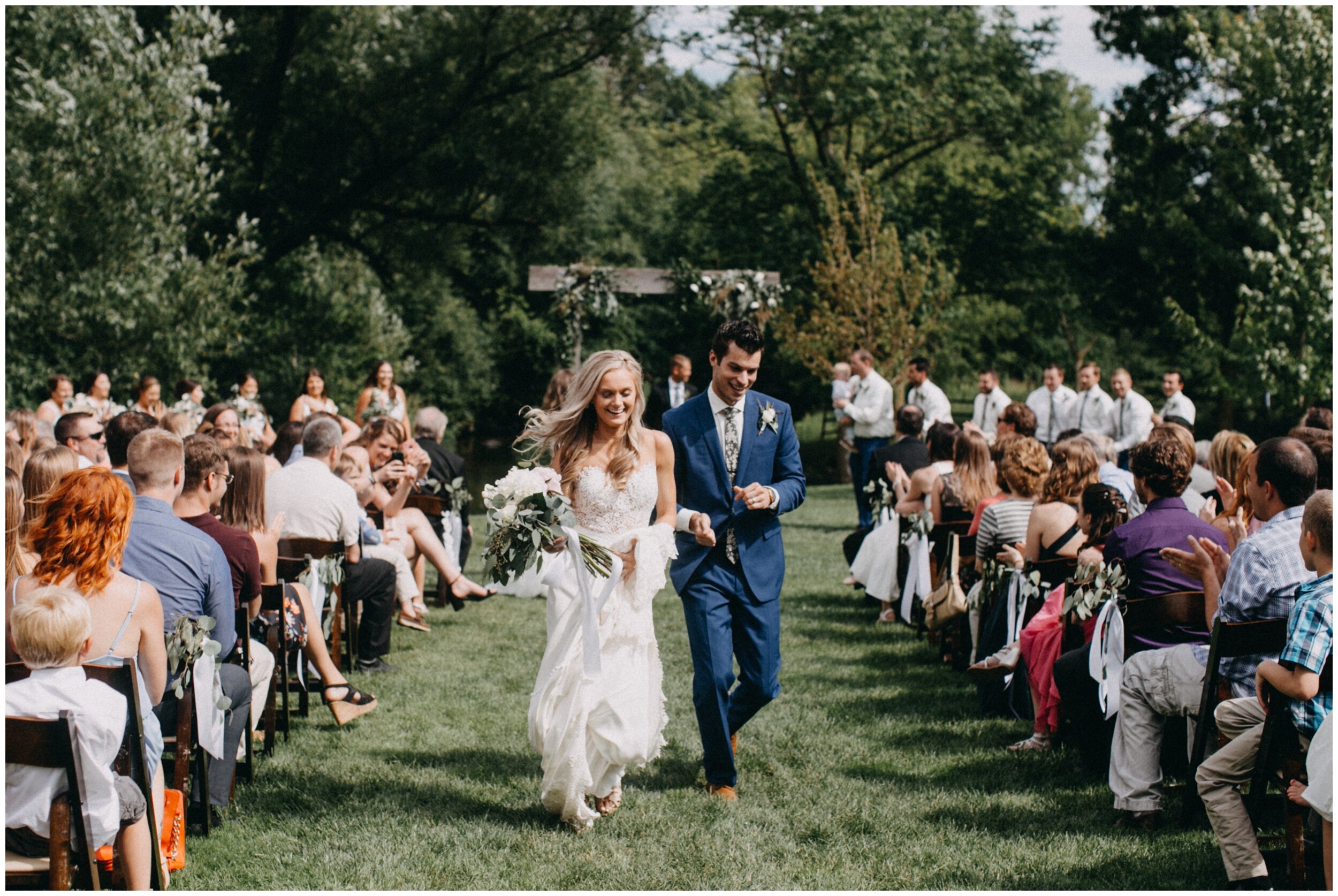 Bride and groom happily walk down aisle after outdoor summer wedding ceremony in Minnesota