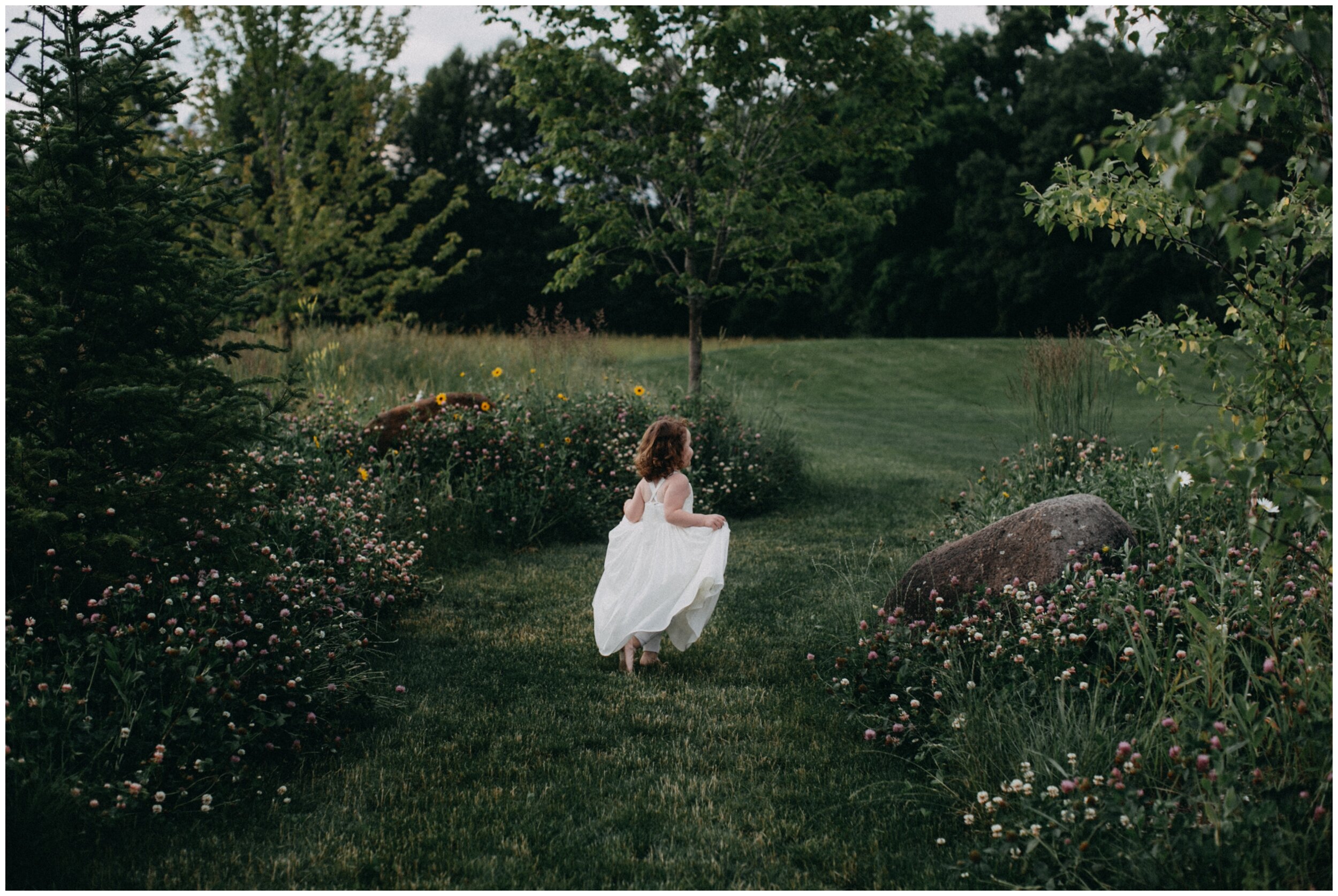 Flower girl walking in garden during outdoor wedding reception