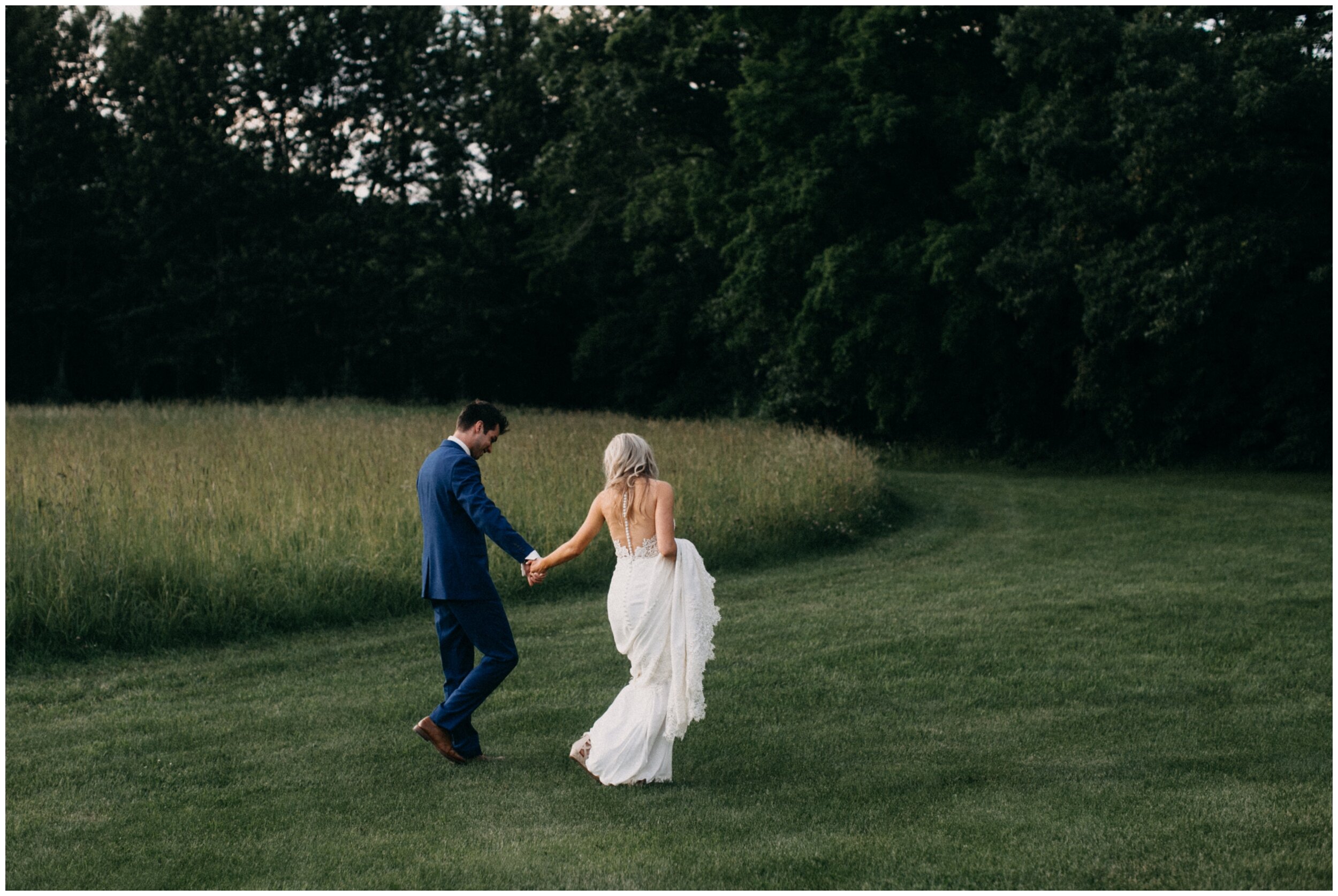 Bride and groom walking in field at Minnesota barn wedding venue