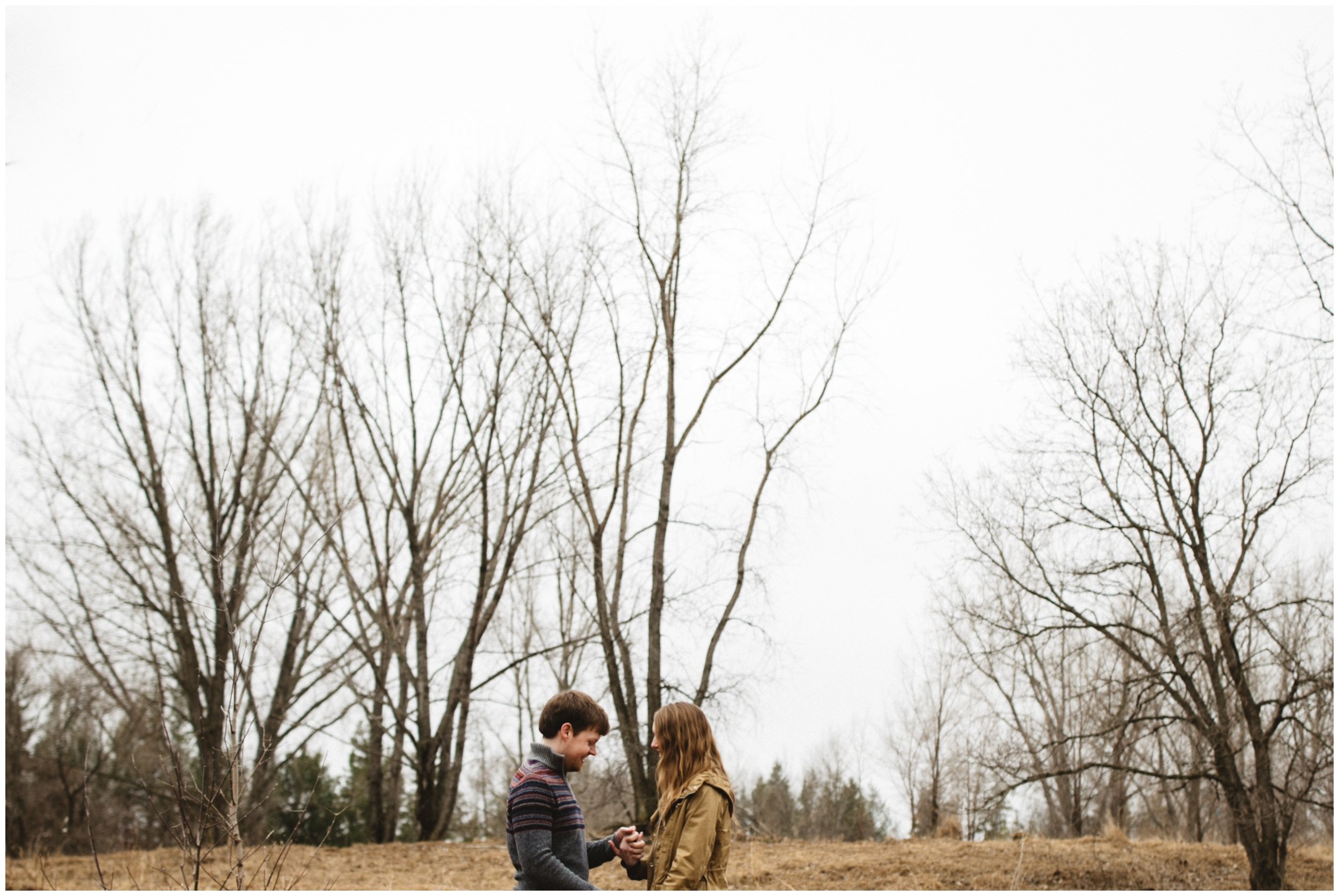 Couple holding hands, standing in the woods during late fall engagement session in Brainerd, Minnesota