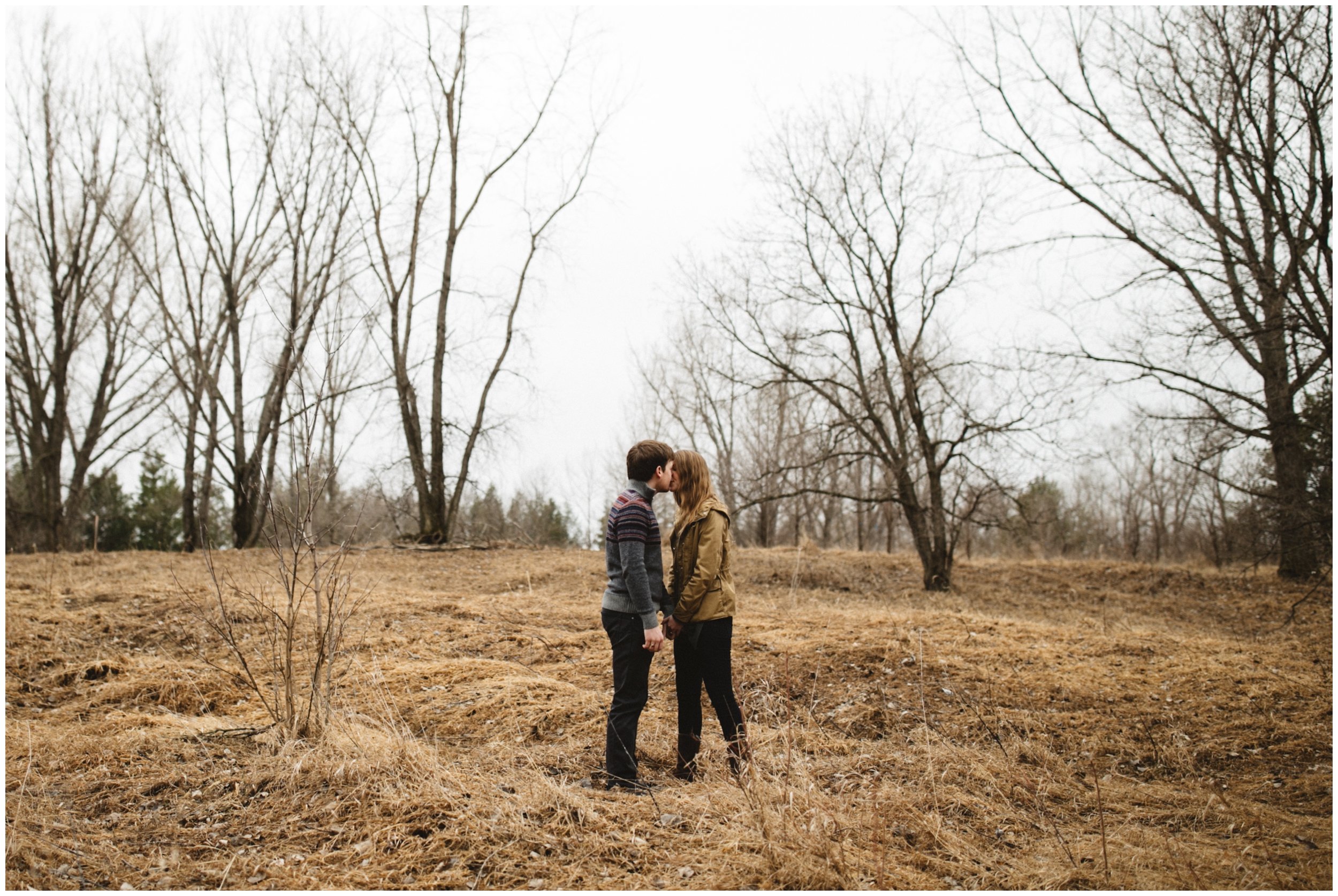 Couple kissing in wooded field during engagement session in Brainerd, Minnesota
