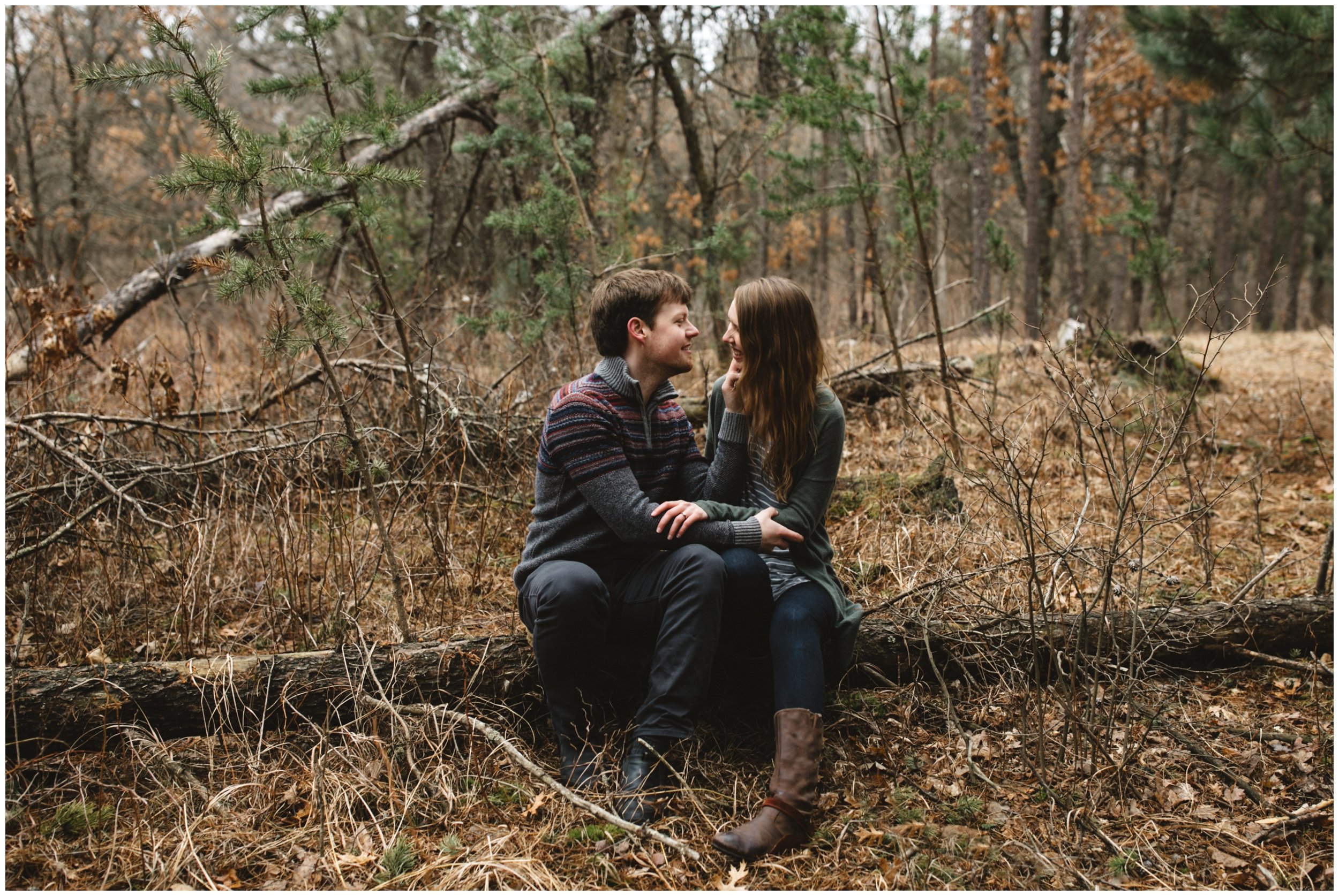 Engagement couple sitting on fallen tree in the woods in Brainerd, Minnesota