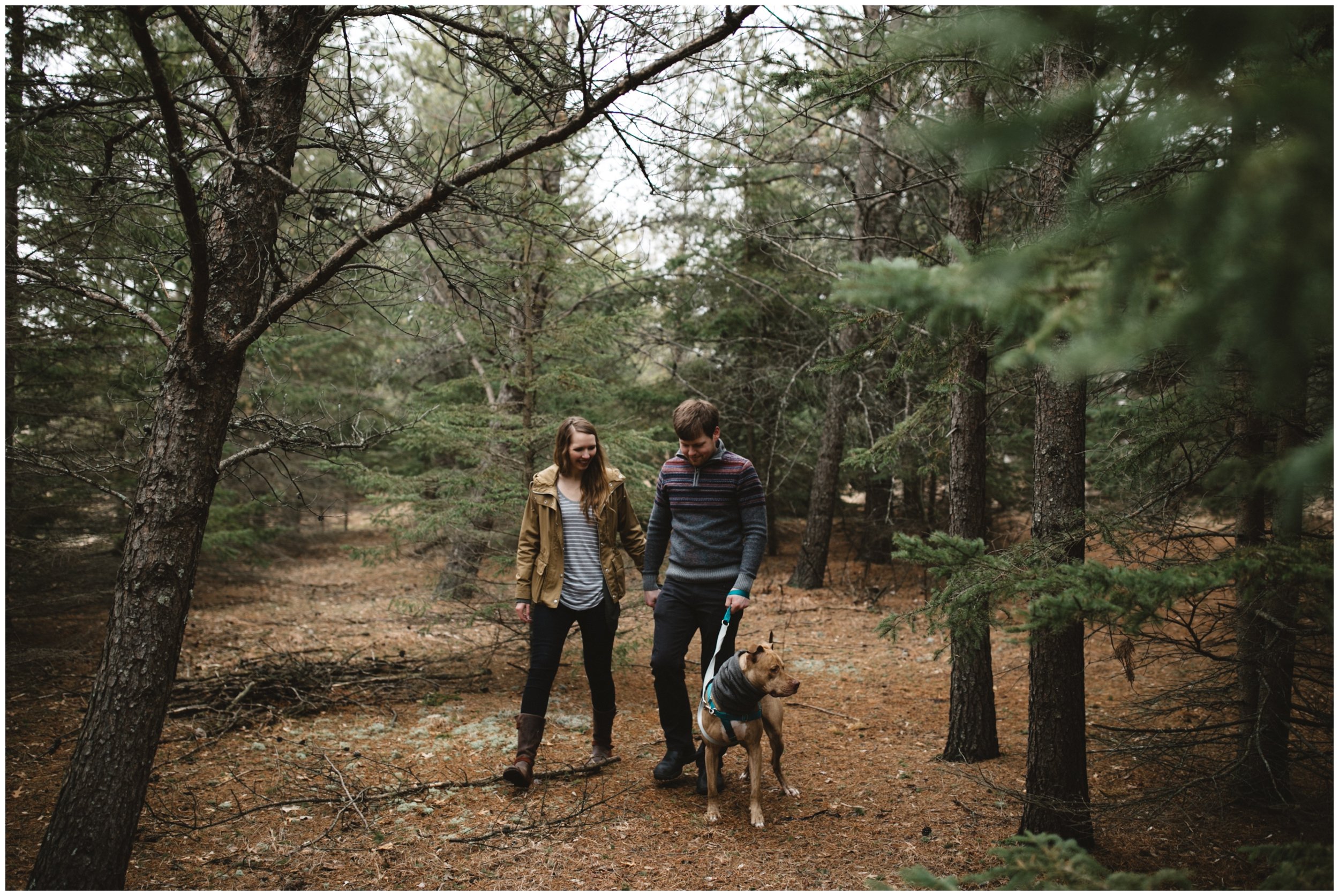 Couple walking their dog in the woods during Brainerd, Minnesota engagement session