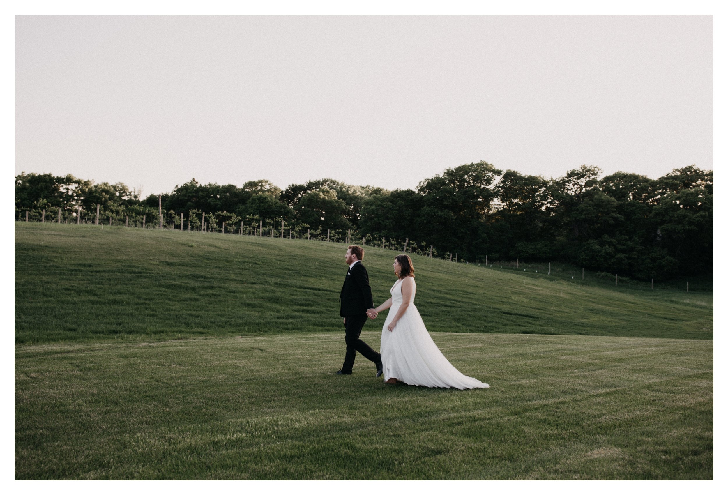 Bride and groom walking to vineyard at Minnesota winery wedding venue