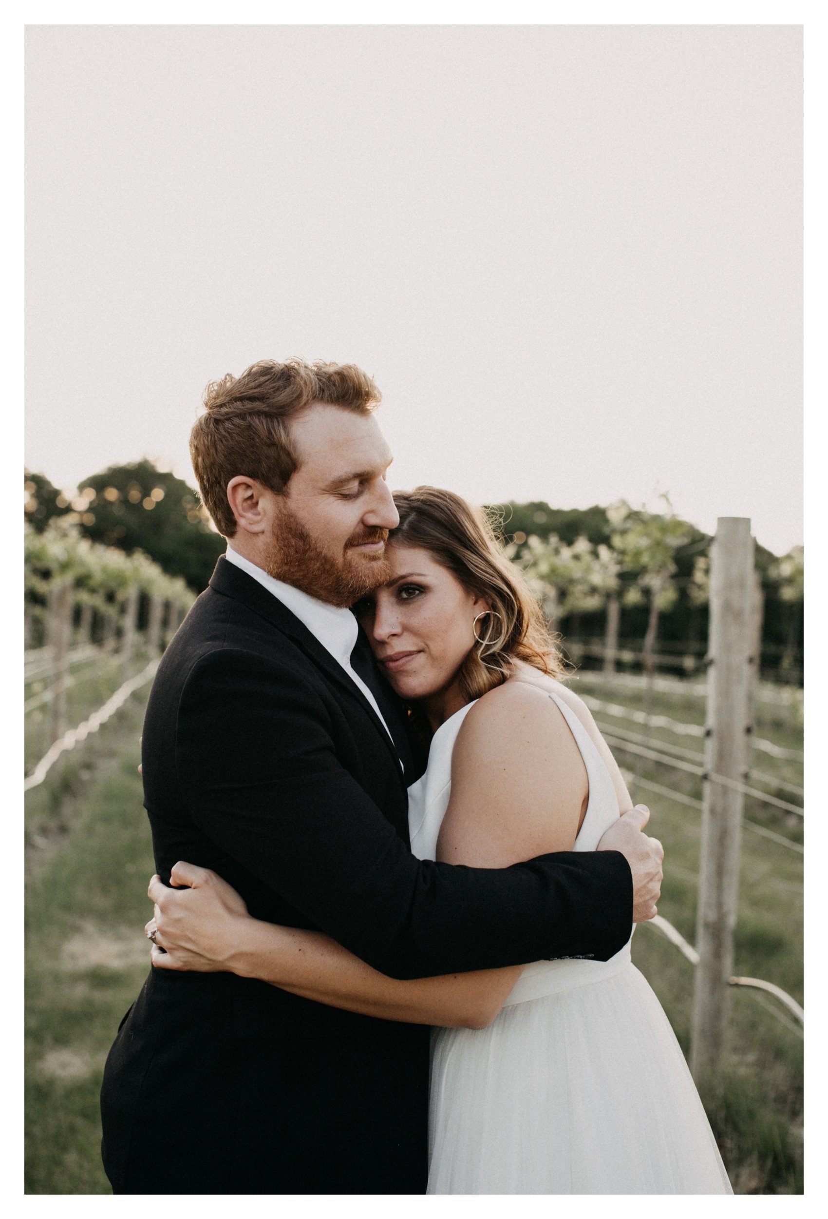 Bride and groom hugging in vineyard during sunset at Minnesota winery wedding