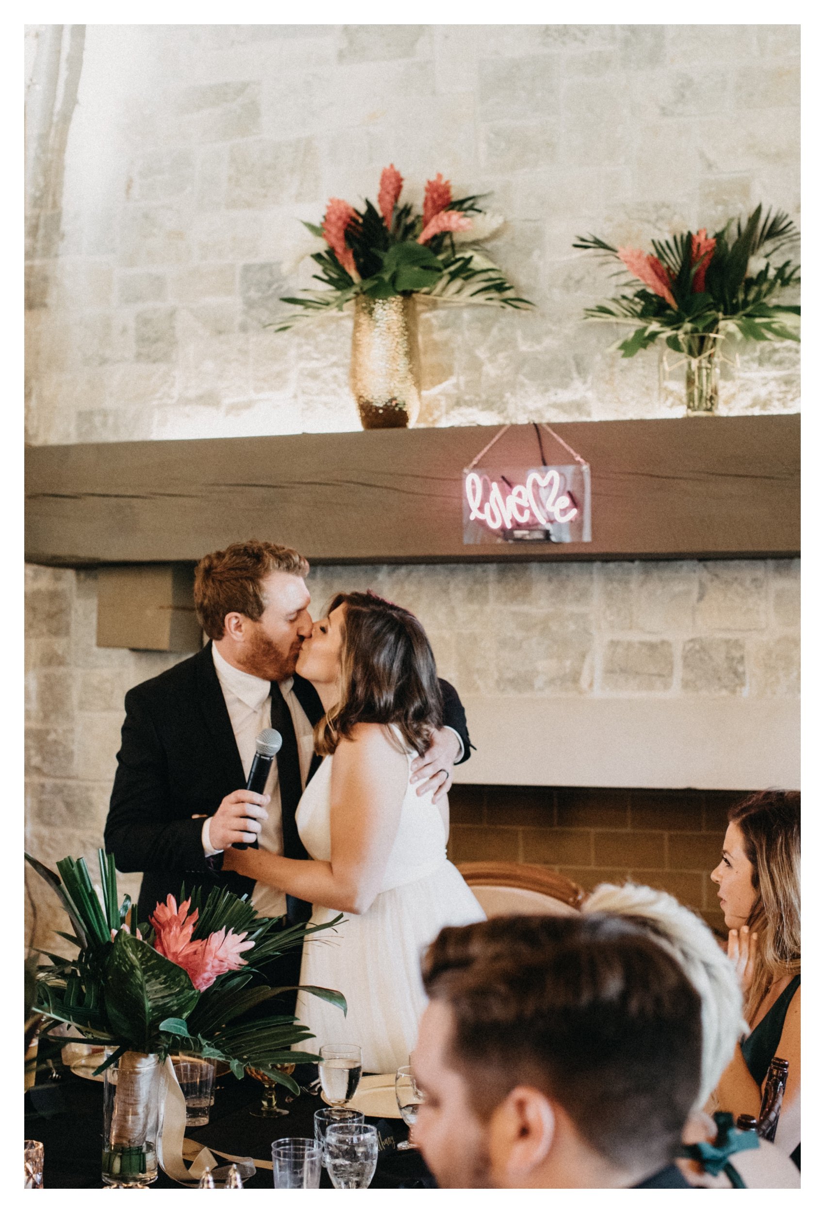 Bride and groom kissing in front of stone fireplace during 7 vines vineyard wedding reception
