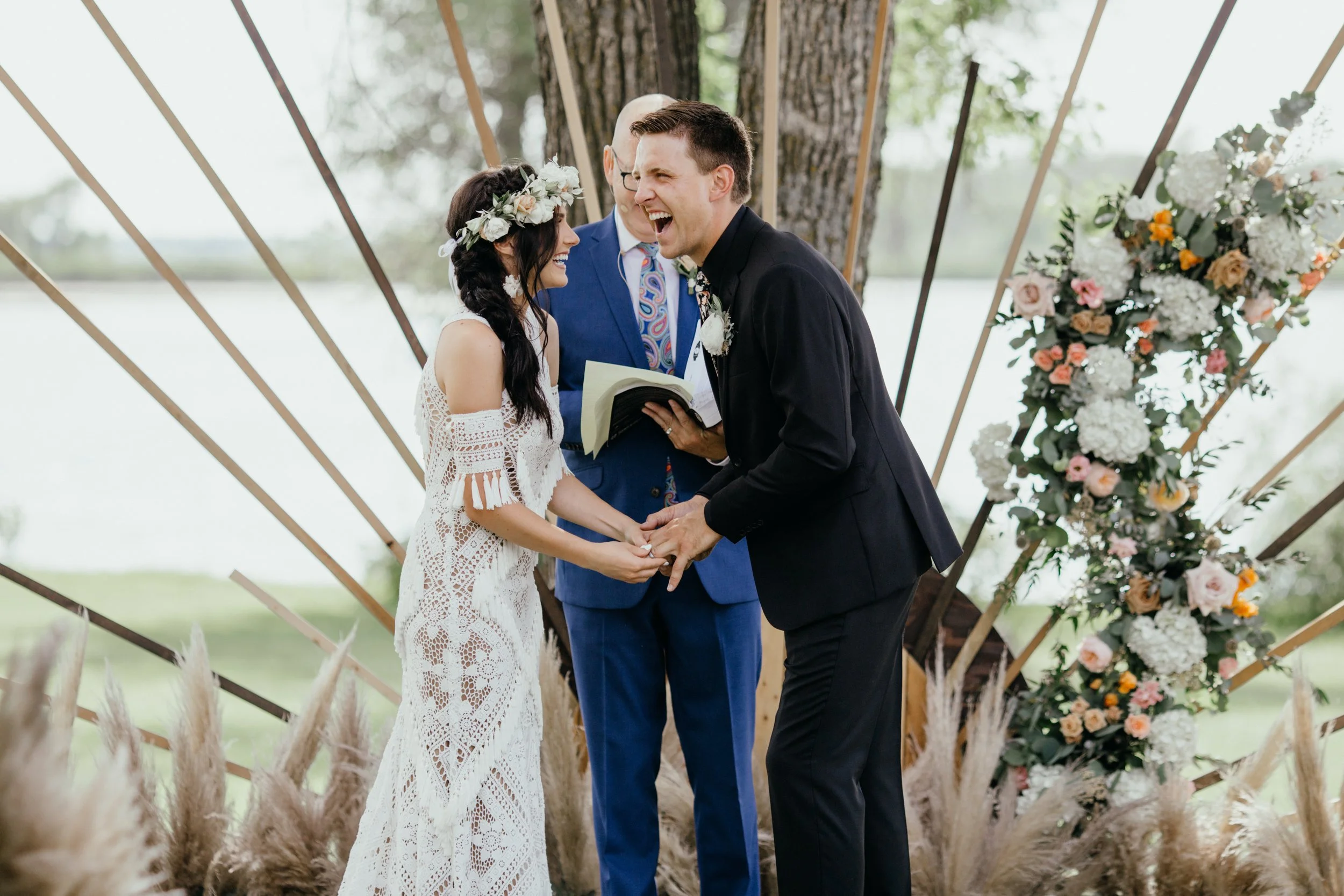 Bride and groom laughing during boho wedding ceremony on the lake in northern Minnesota