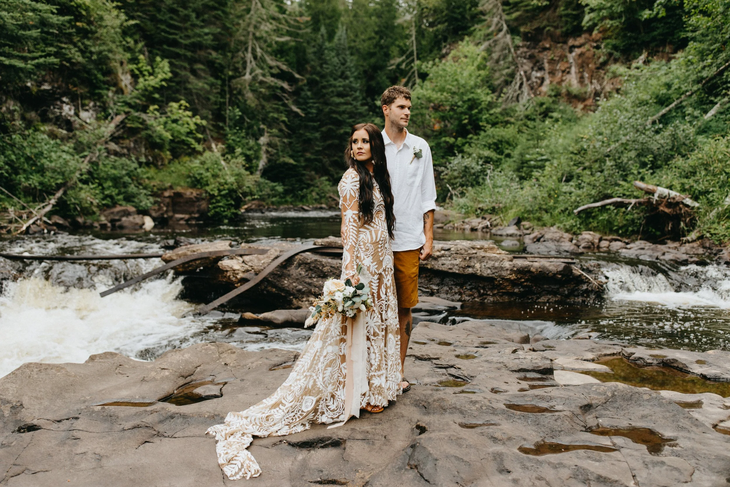 Bride and groom on wedding day standing next to waterfall in Lutsen, Minnesota